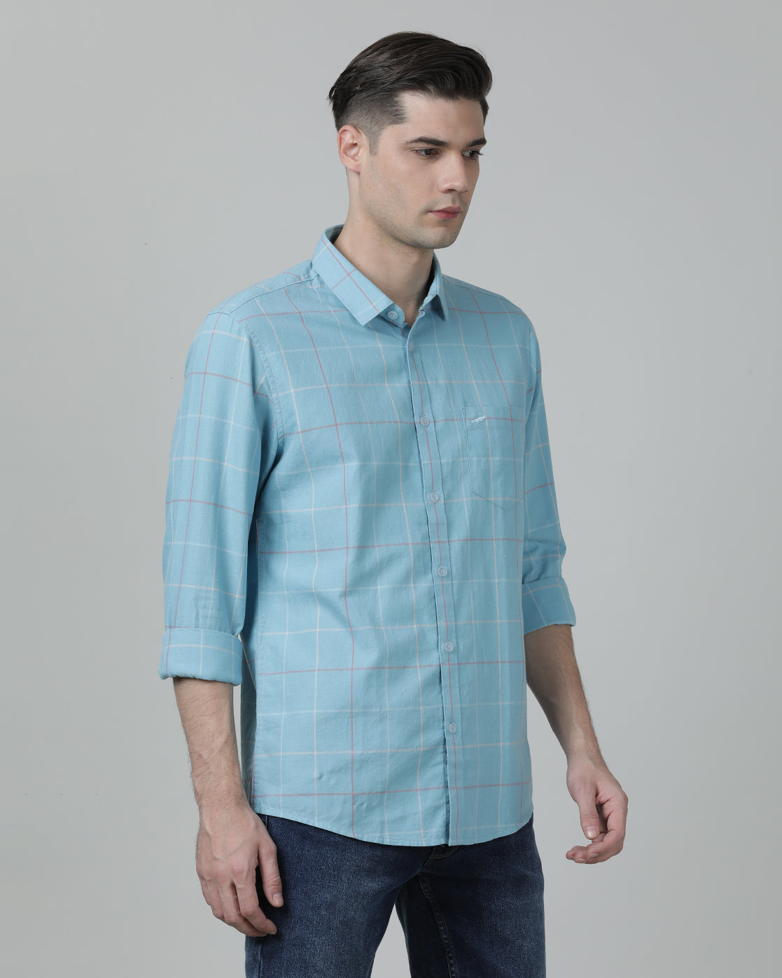 Man wearing a blue casual blue checked full sleeve 100% cotton shirt on a light gray background