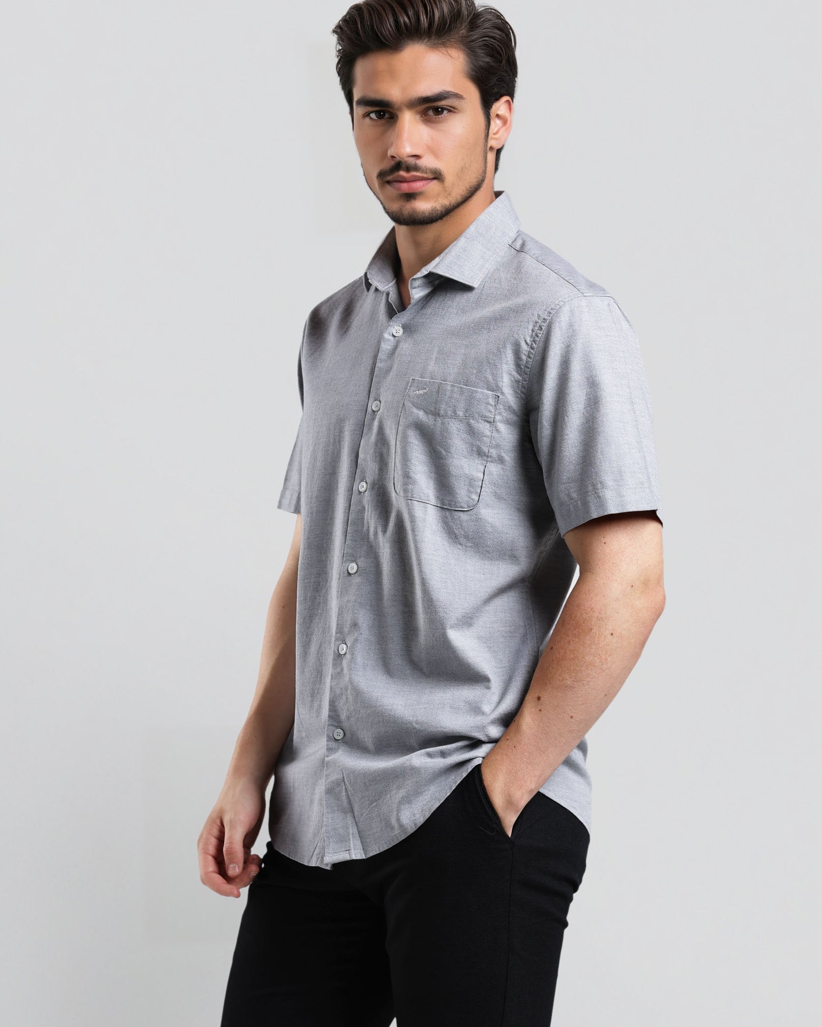 Man wearing a gray short-sleeve shirt and black pants on a light gray background