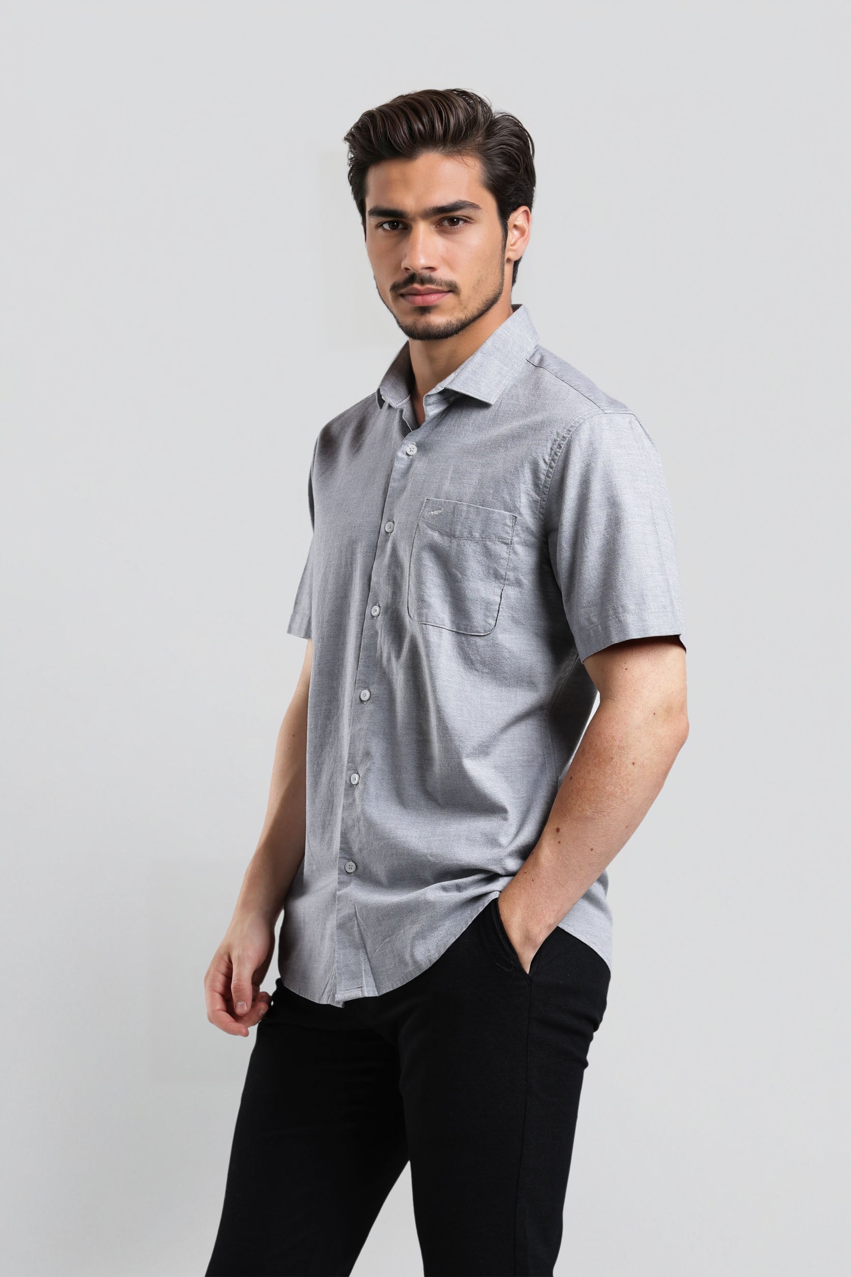 Man wearing a gray short-sleeve shirt and black pants on a light gray background