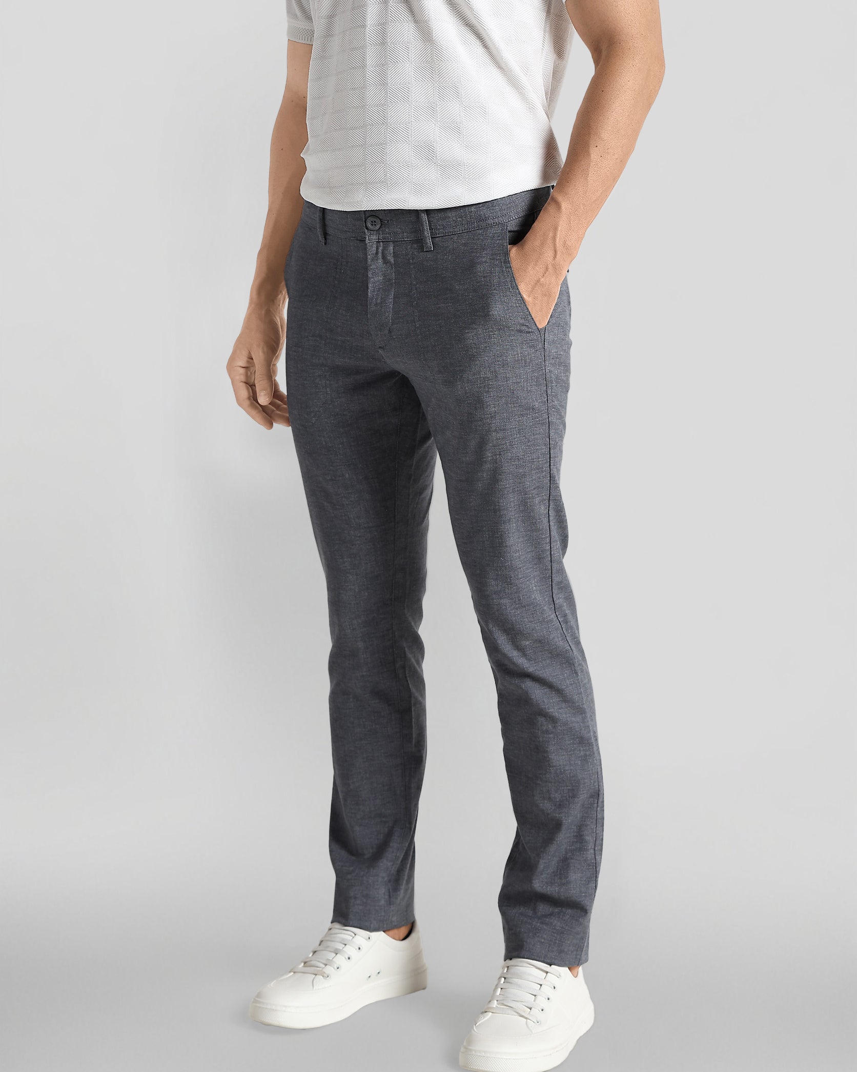 Person wearing gray pants and white shoes on a light gray background