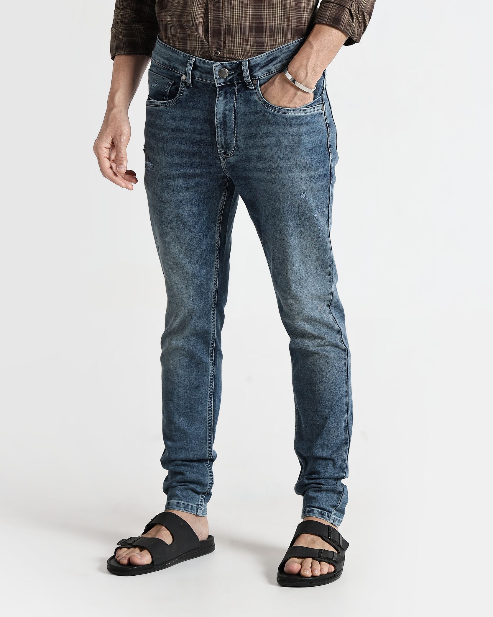 Person wearing blue jeans and a plaid shirt on a white background