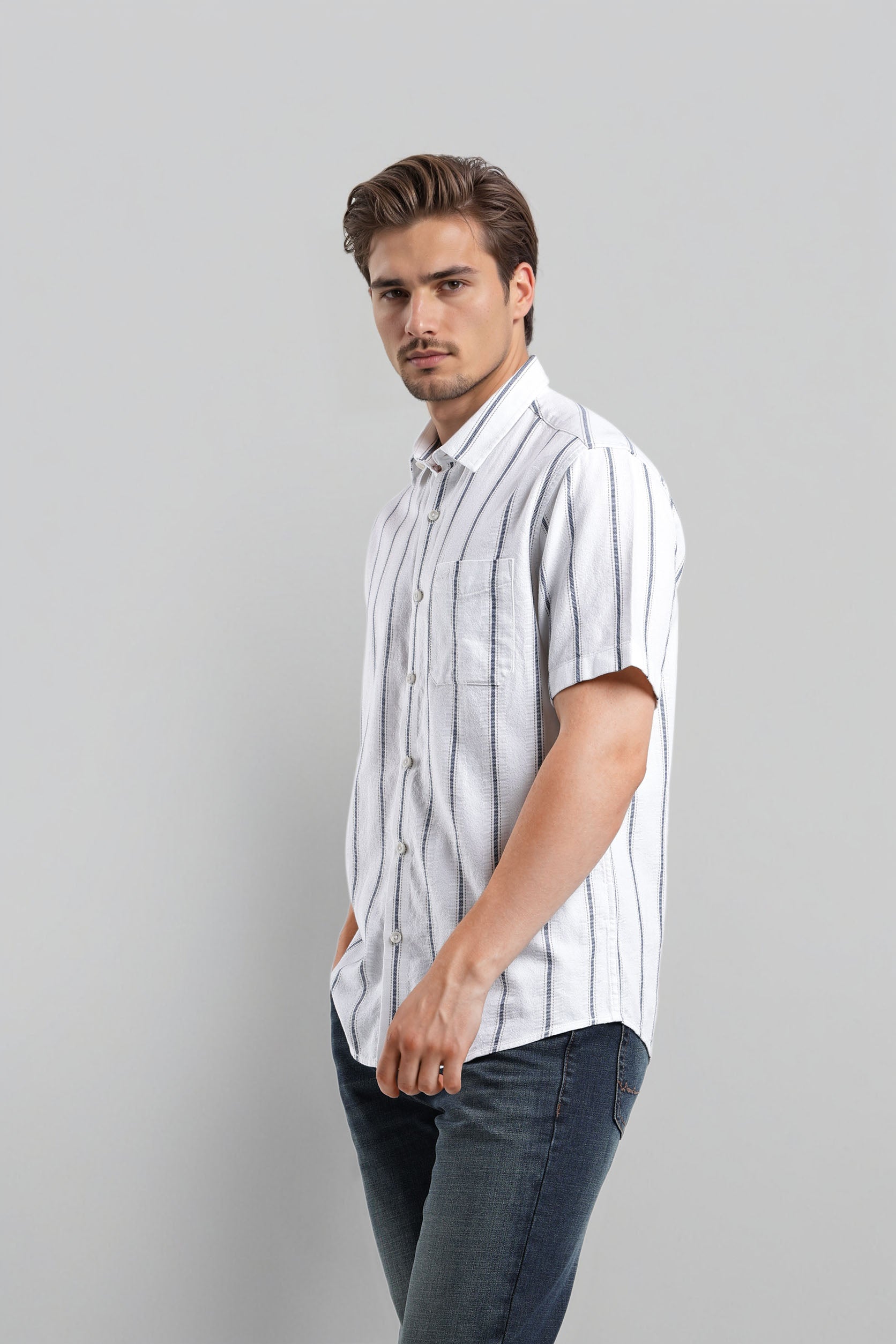 Man wearing a white striped shirt and dark jeans against a gray background