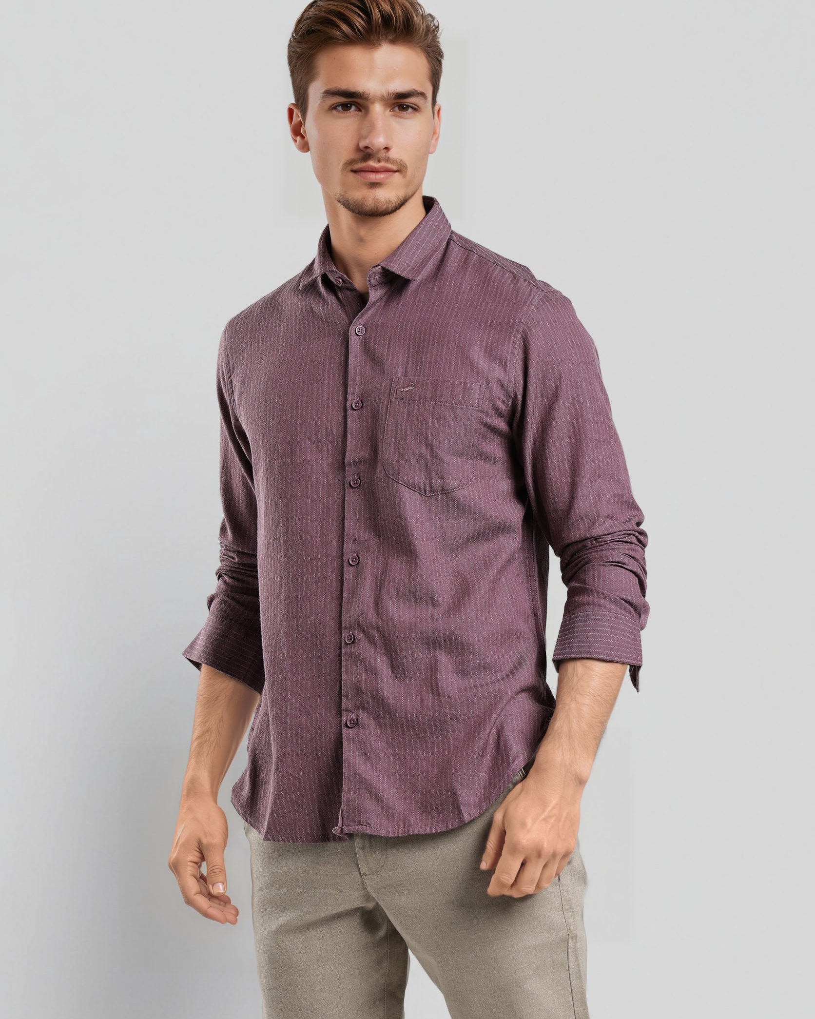 Man wearing a purple shirt and beige pants against a light gray background