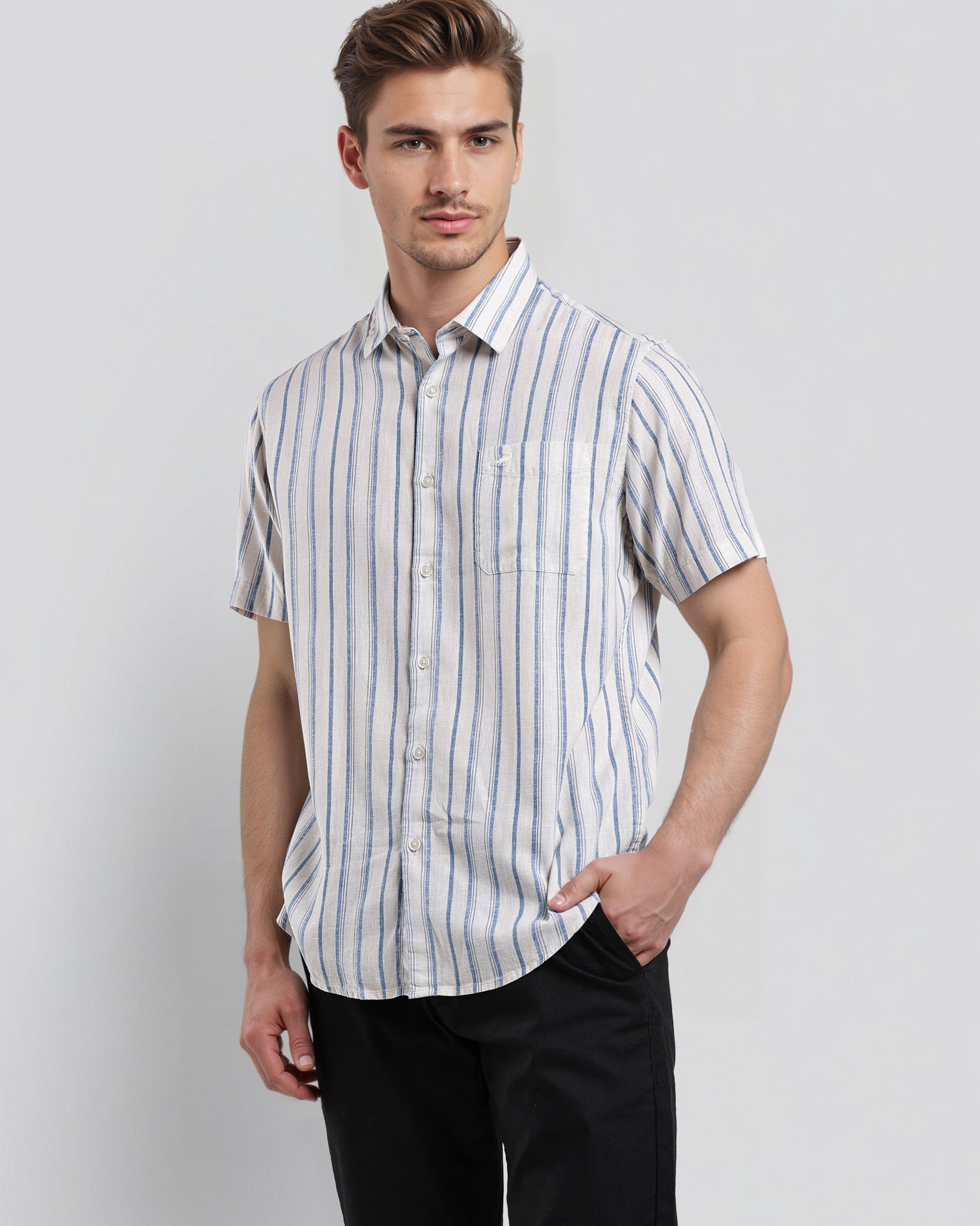 Man wearing a striped shirt and black pants on a light gray background