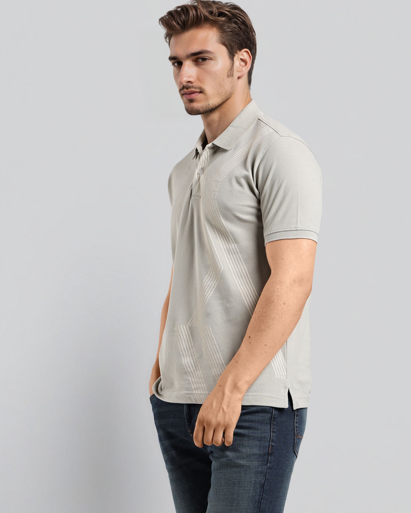 Man wearing a light gray polo shirt and dark jeans on a plain background