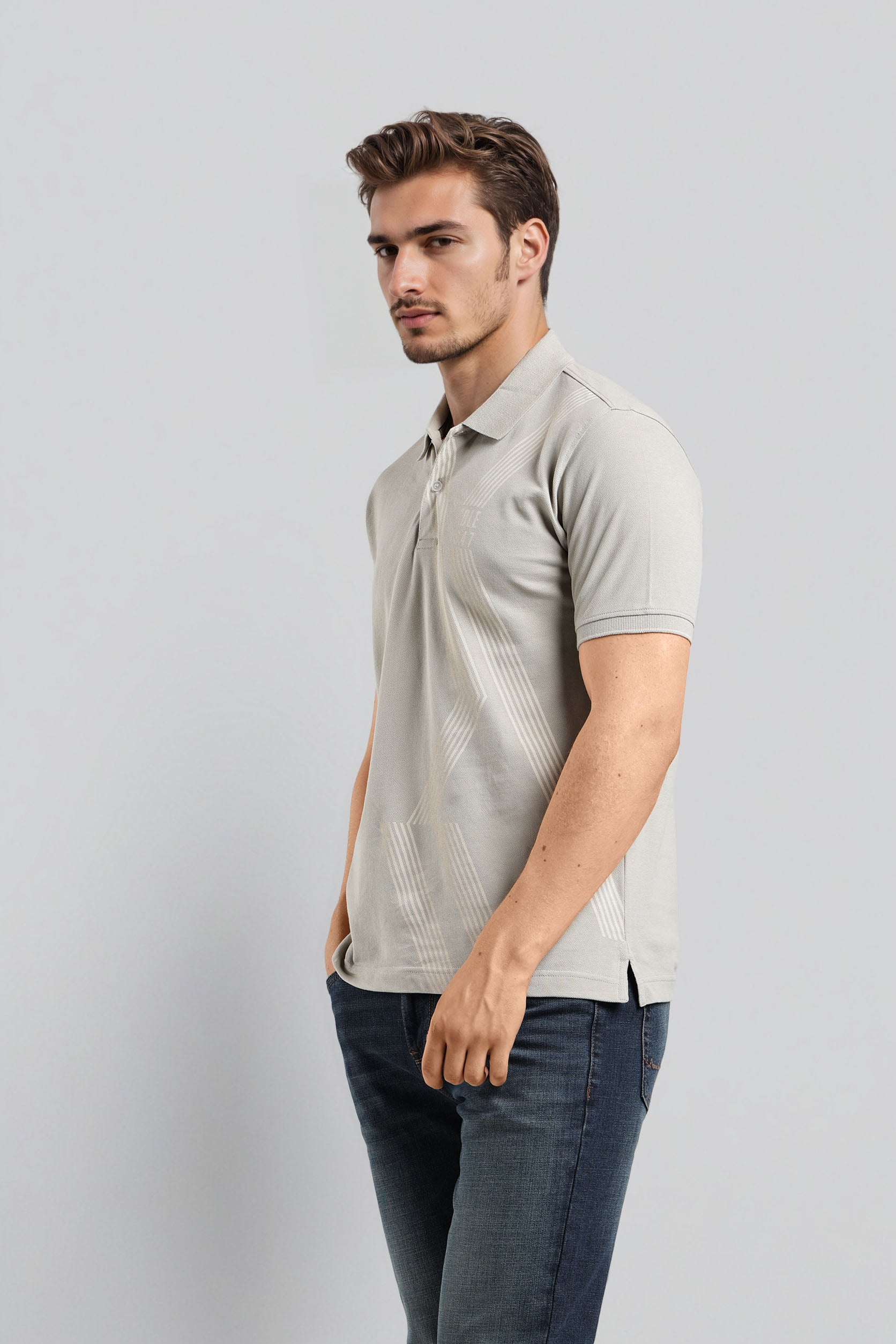 Man wearing a light gray polo shirt and dark jeans on a plain background