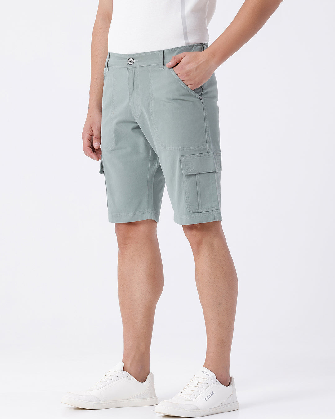 Man wearing a olive garment dyed cargo shorts in olive on a light gray background