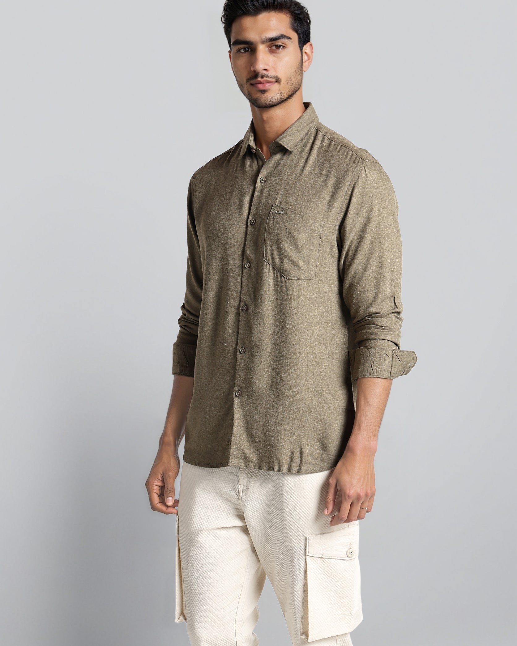 Man wearing a green shirt and white pants on a gray background