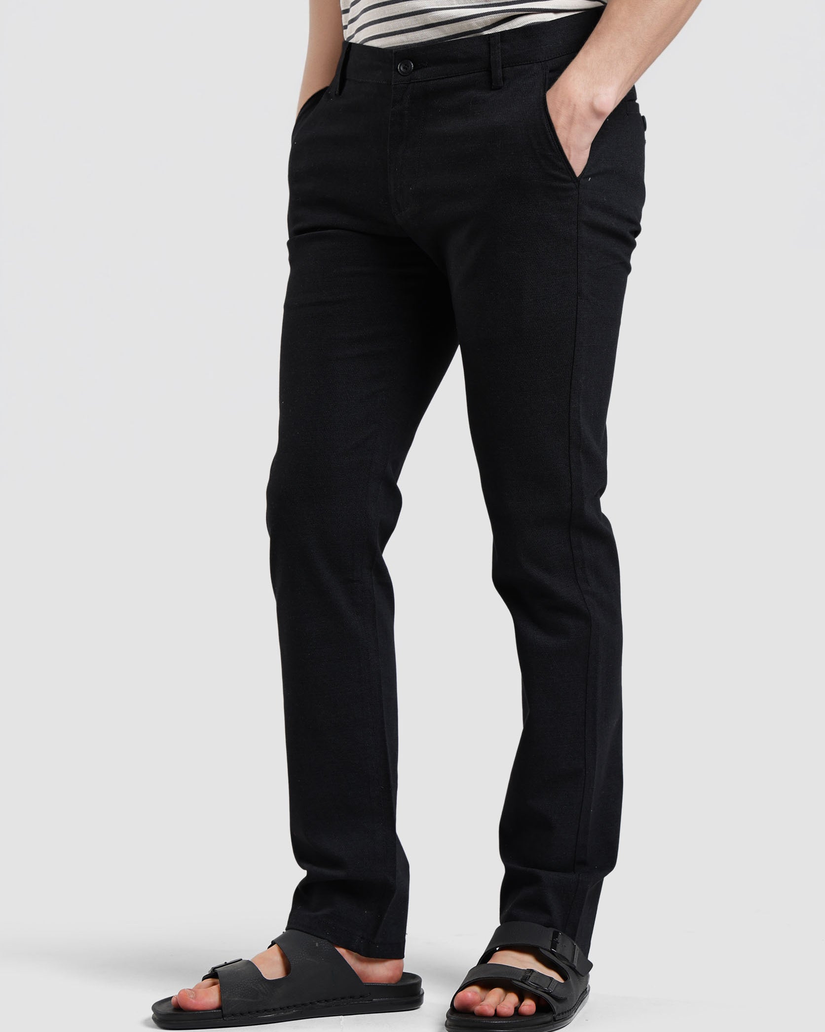 Person wearing black pants and sandals on a white background