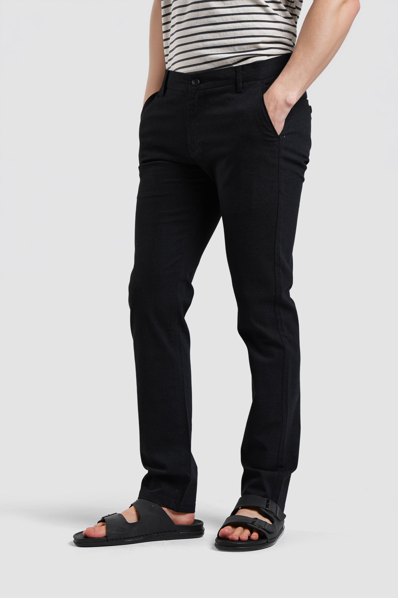 Person wearing black pants and sandals on a white background