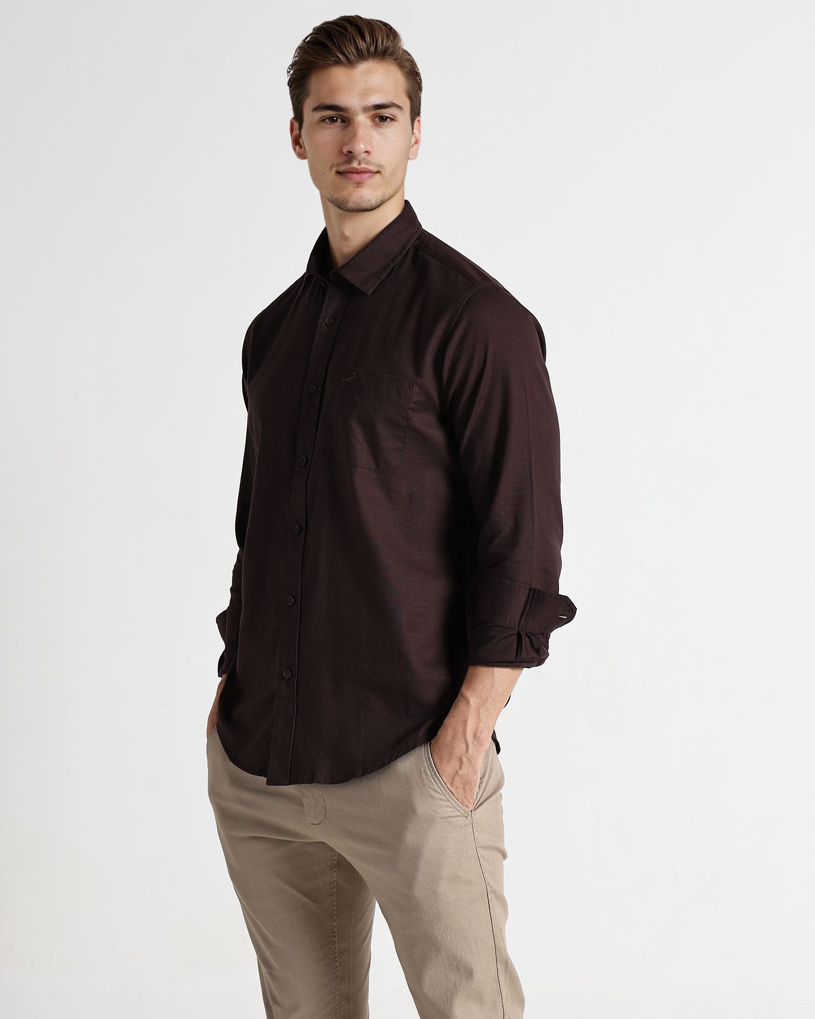 Man wearing a dark brown shirt and beige pants on a white background