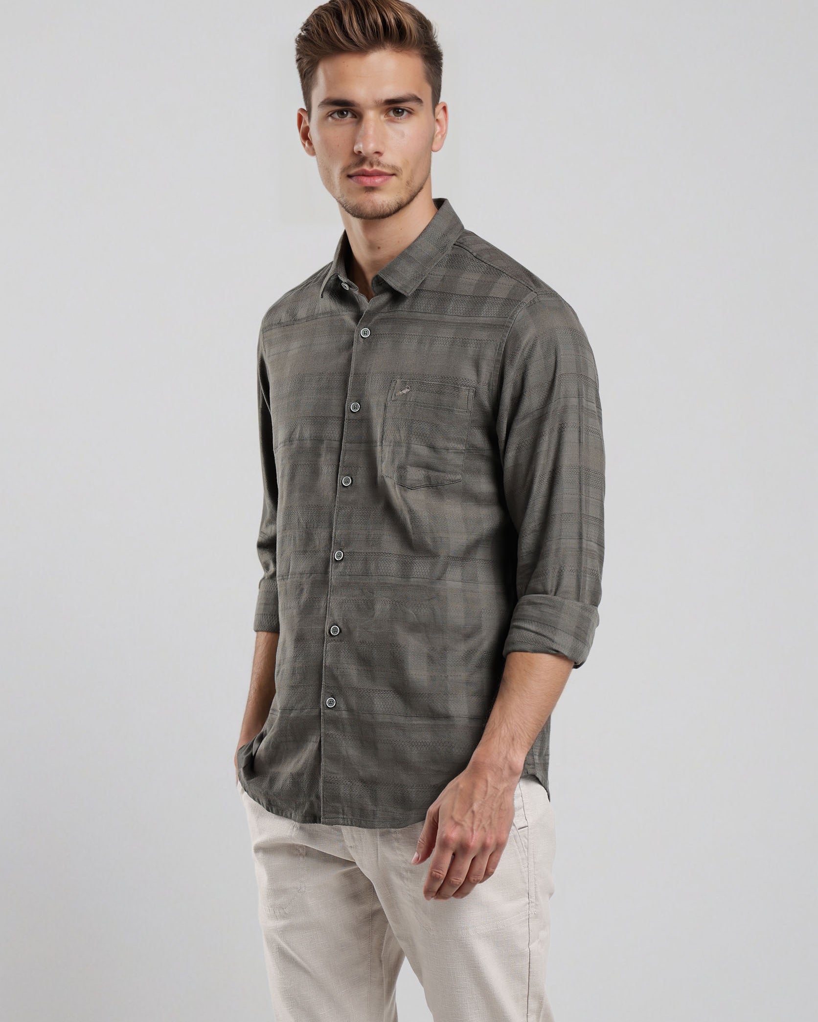 Man wearing a gray plaid shirt and light-colored pants on a white background