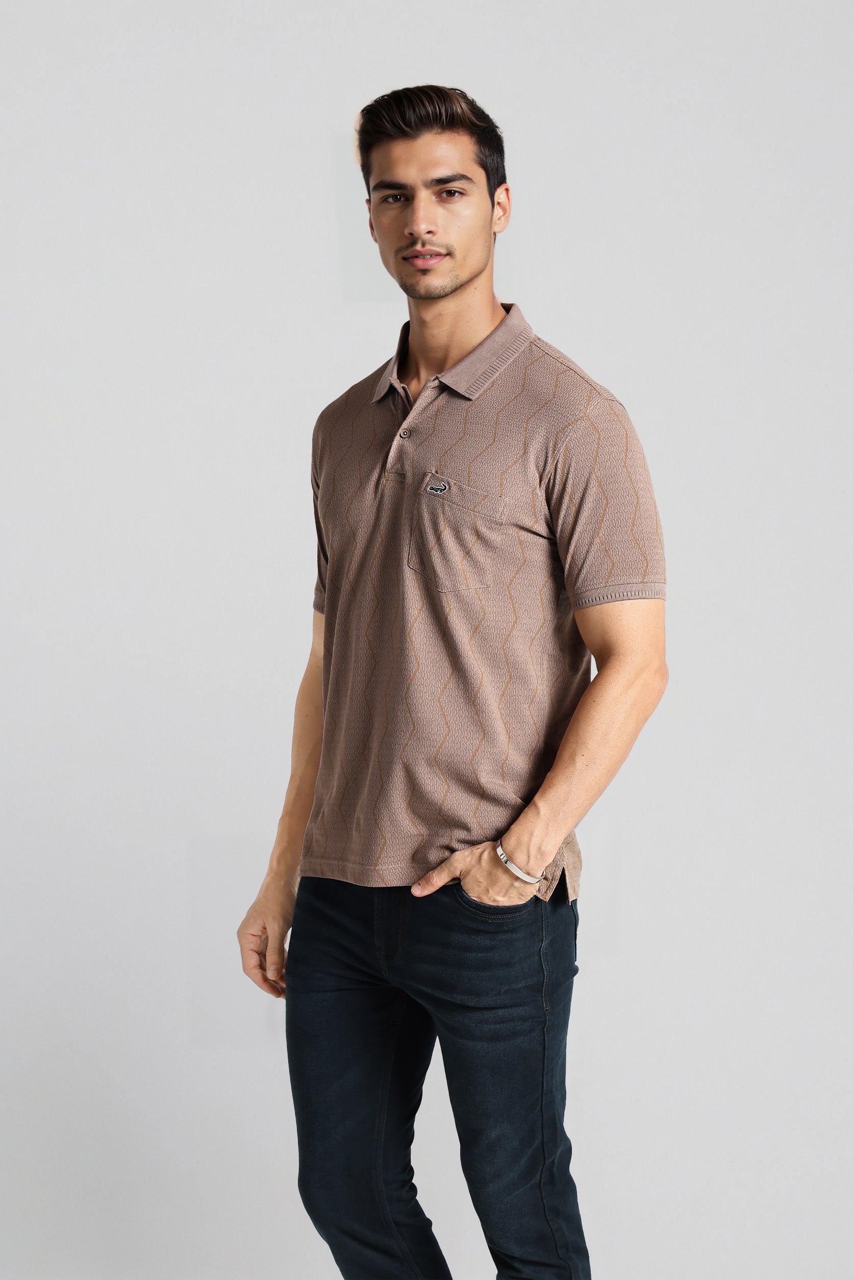 Man wearing a brown polo shirt and dark pants on a light gray background