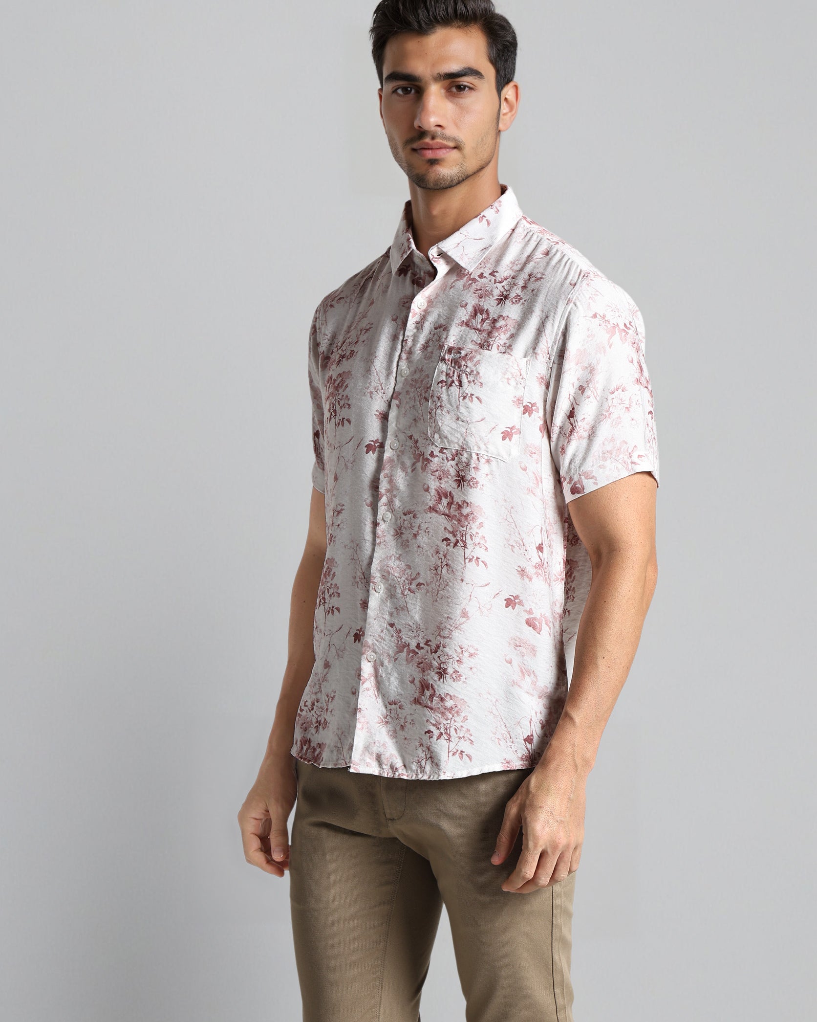 Man wearing a patterned shirt and beige pants on a gray background