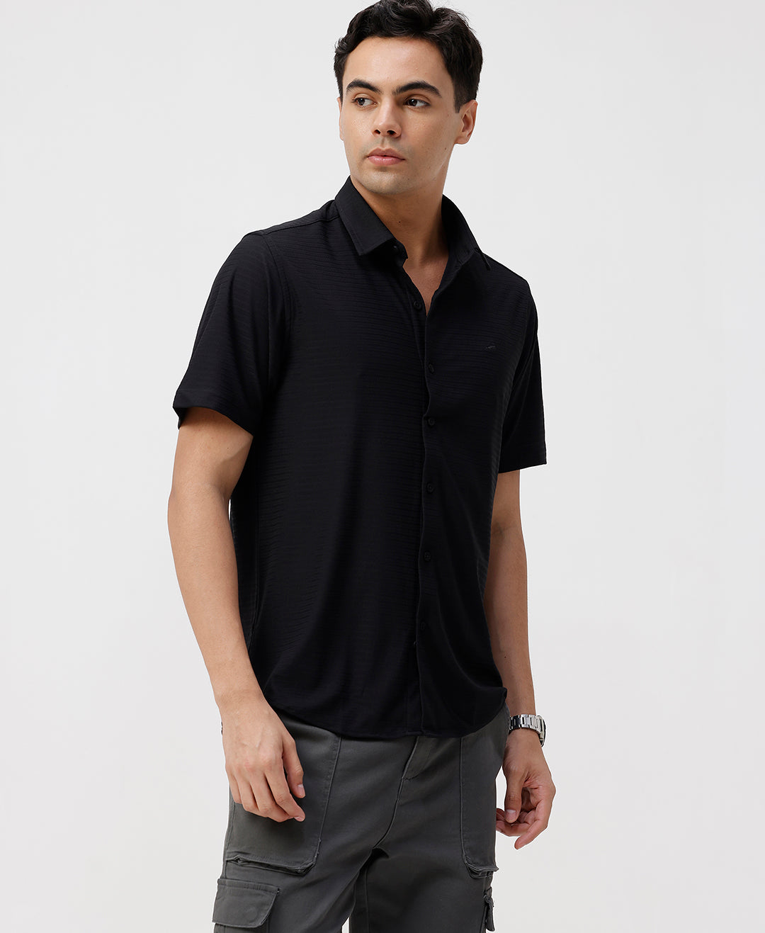 Man wearing a black solid black cotton shirt with casual styling on a gray background