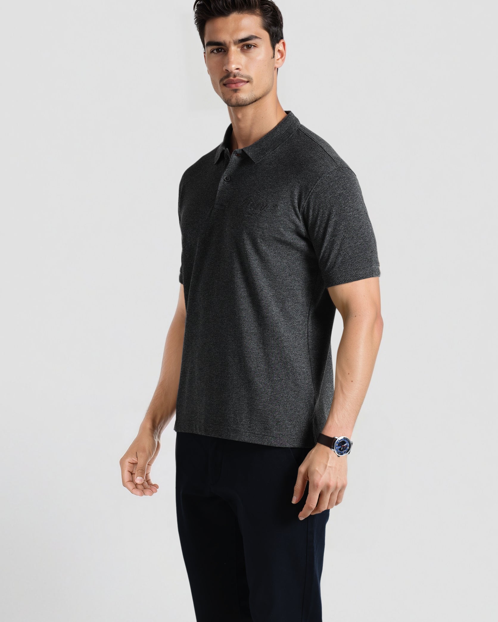 Man wearing a dark gray polo shirt and black pants on a light gray background