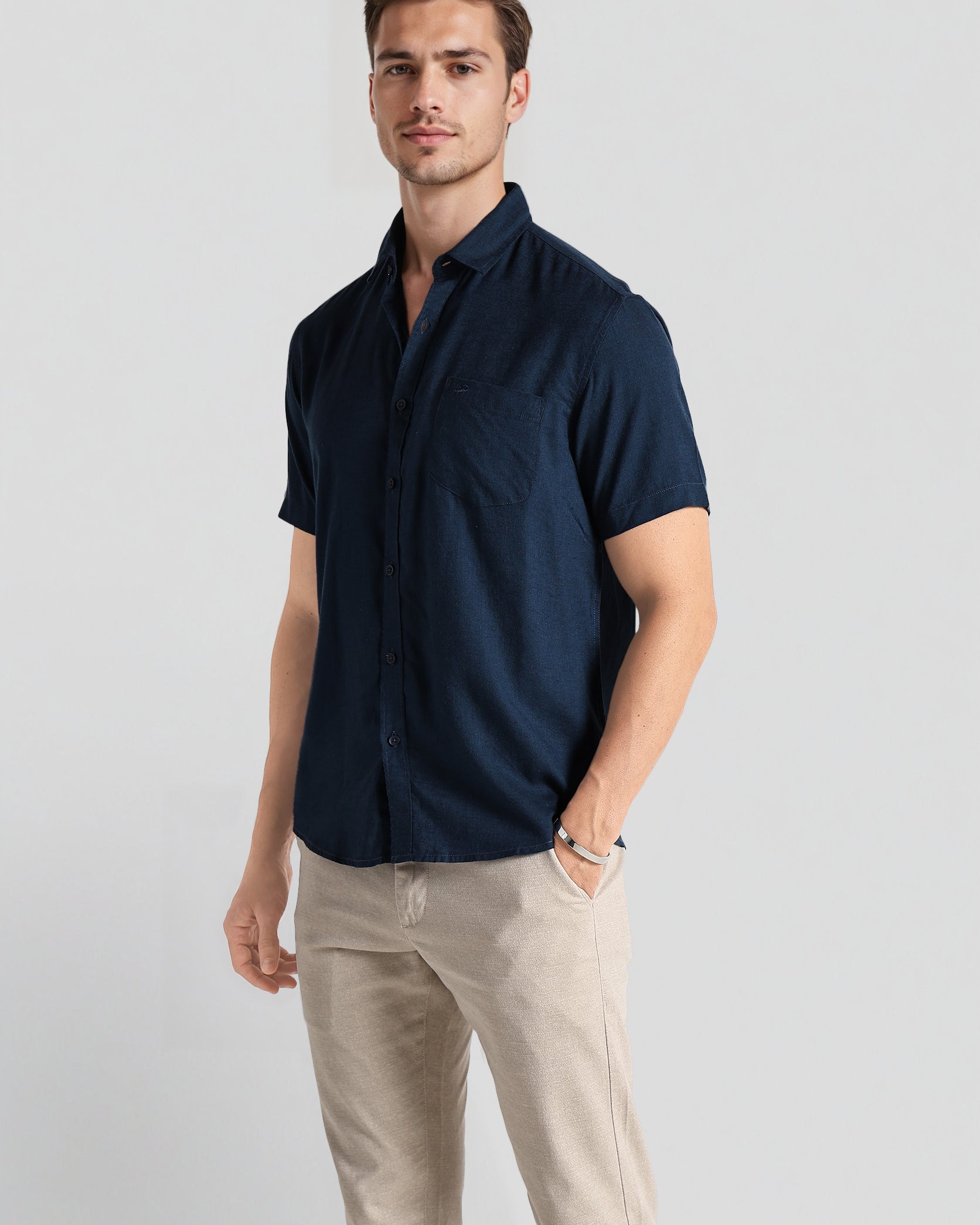 Man wearing a navy blue shirt and beige pants on a light gray background