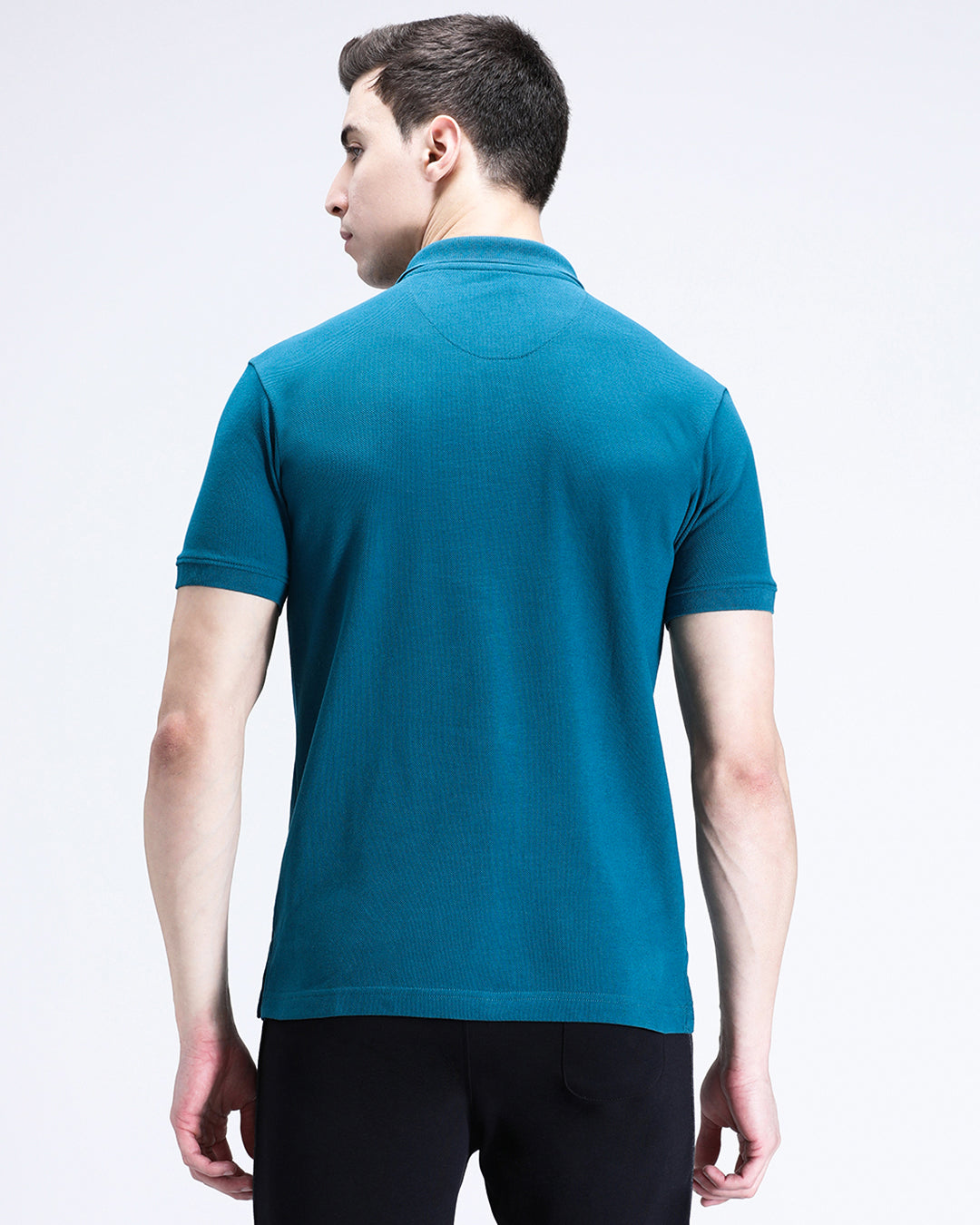 Man wearing a blue blue coral solid polo t shirt with casual styling on a gray background
