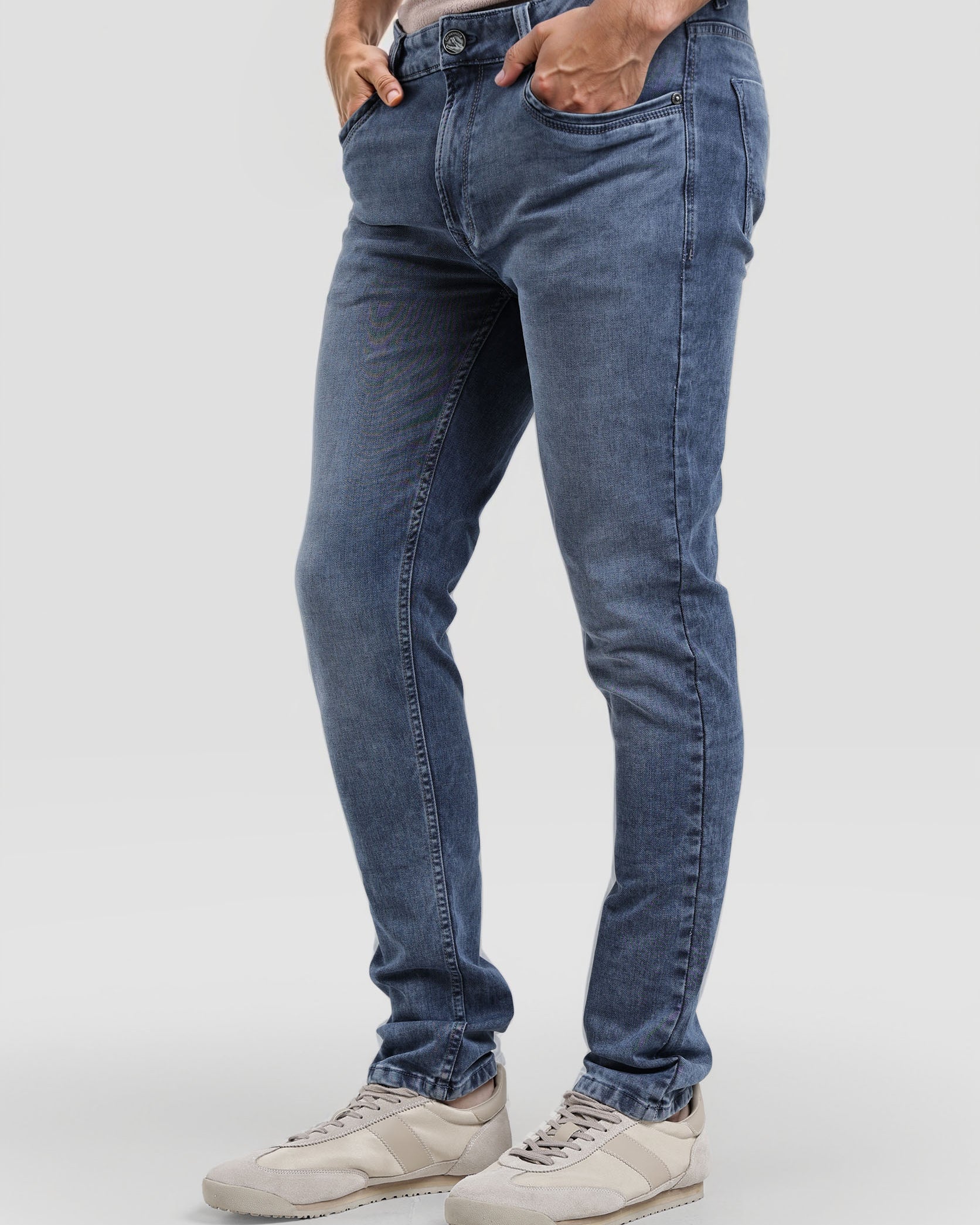 Person wearing blue jeans and white sneakers on a white background