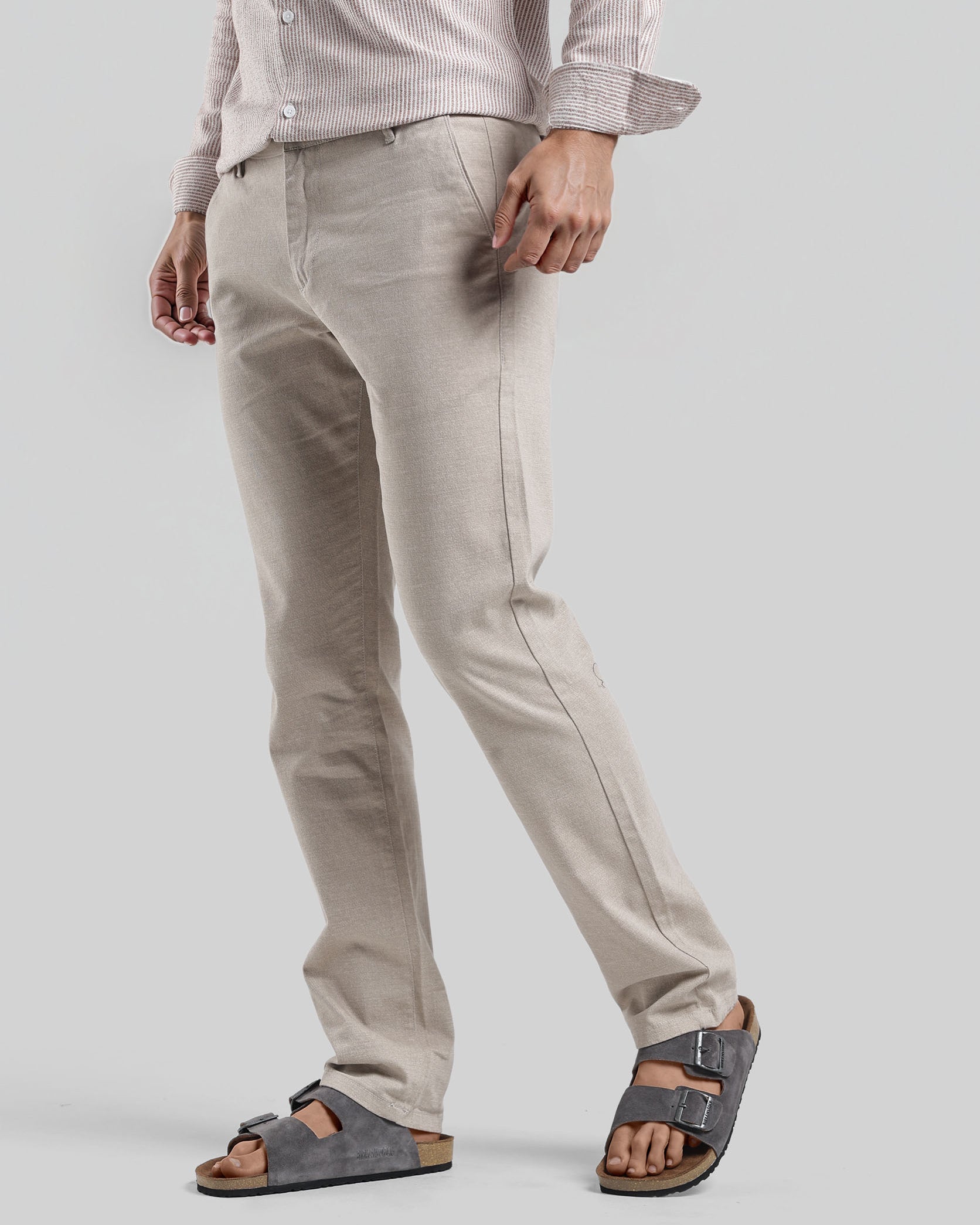 Person wearing light-colored pants and sandals on a plain background