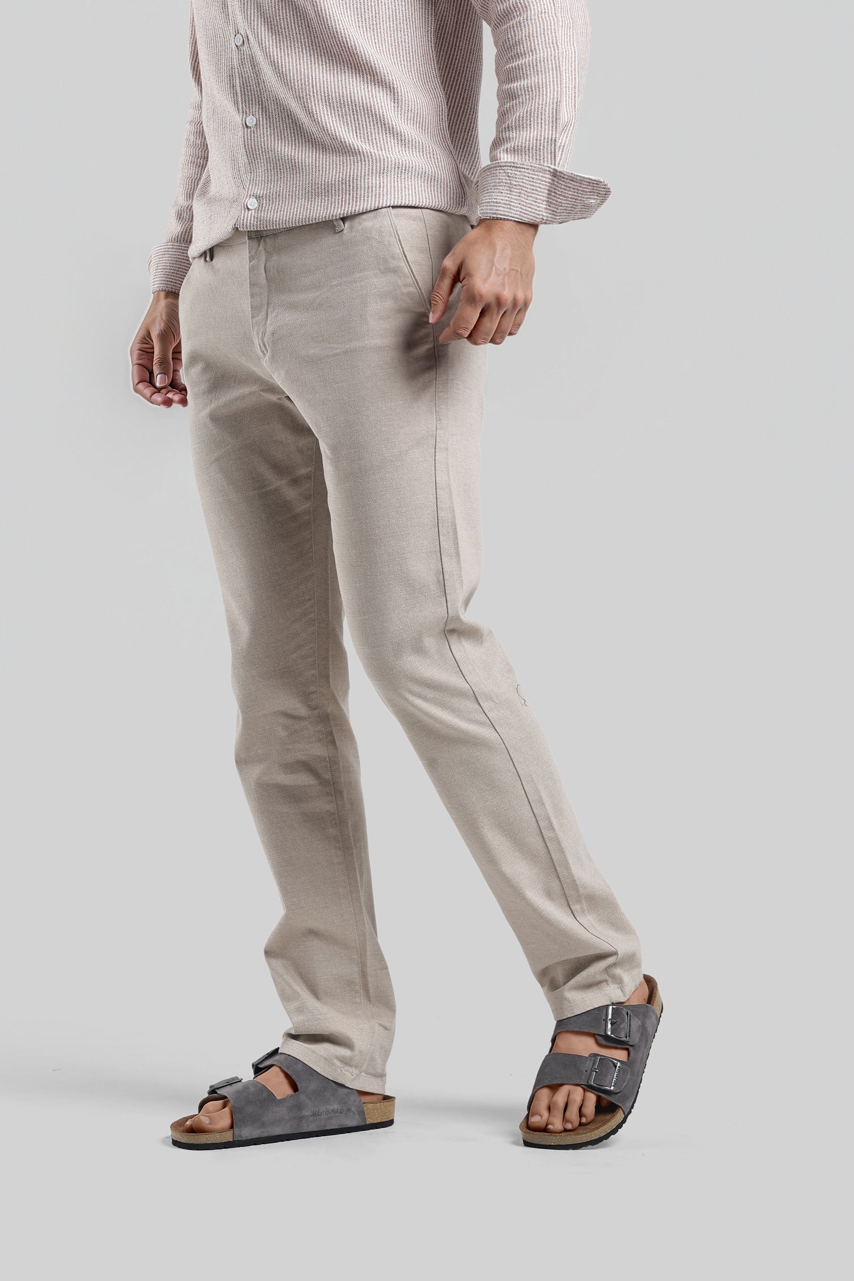 Person wearing light-colored pants and sandals on a plain background