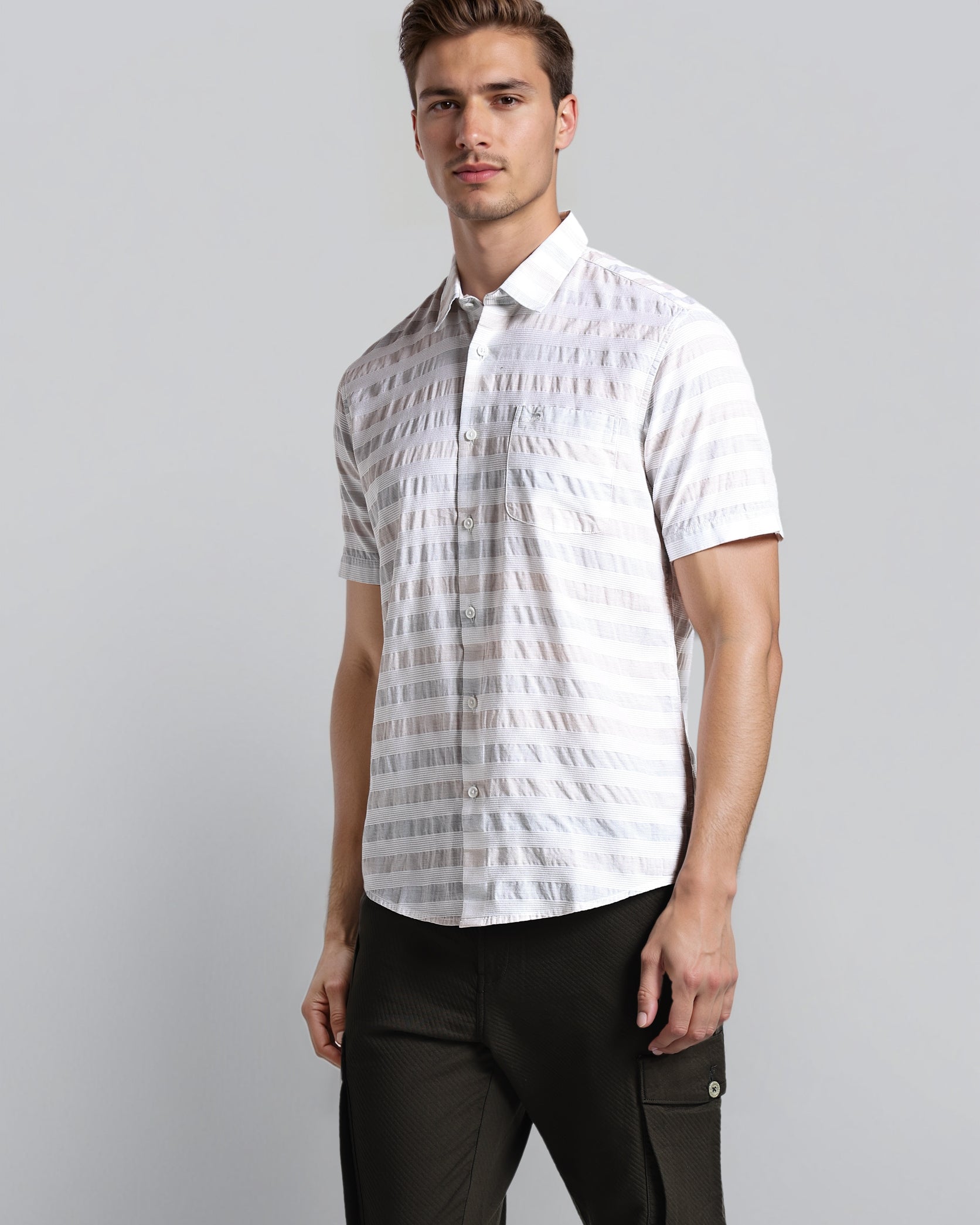 Man wearing a white patterned shirt and black pants on a gray background