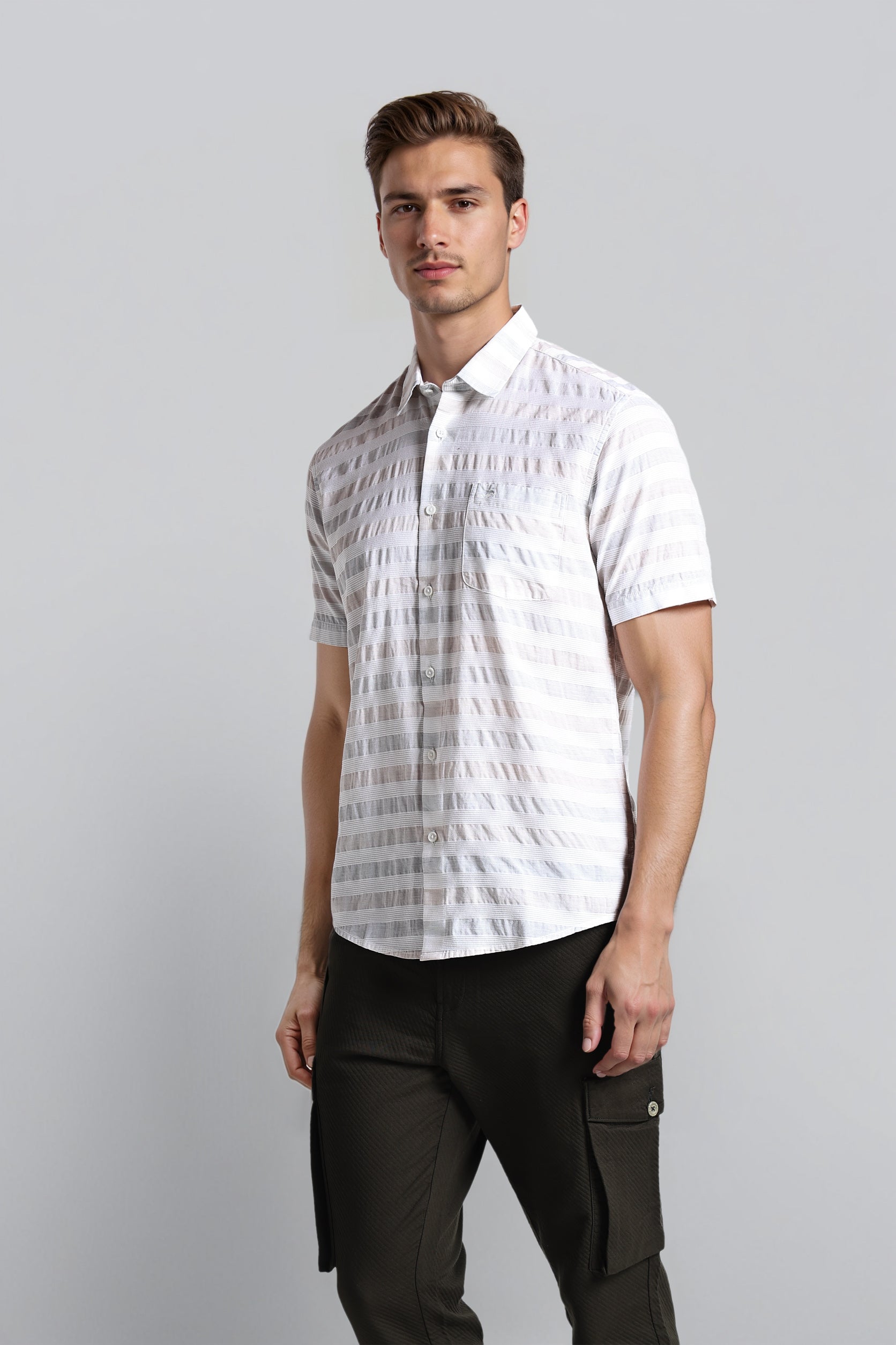 Man wearing a white patterned shirt and black pants on a gray background