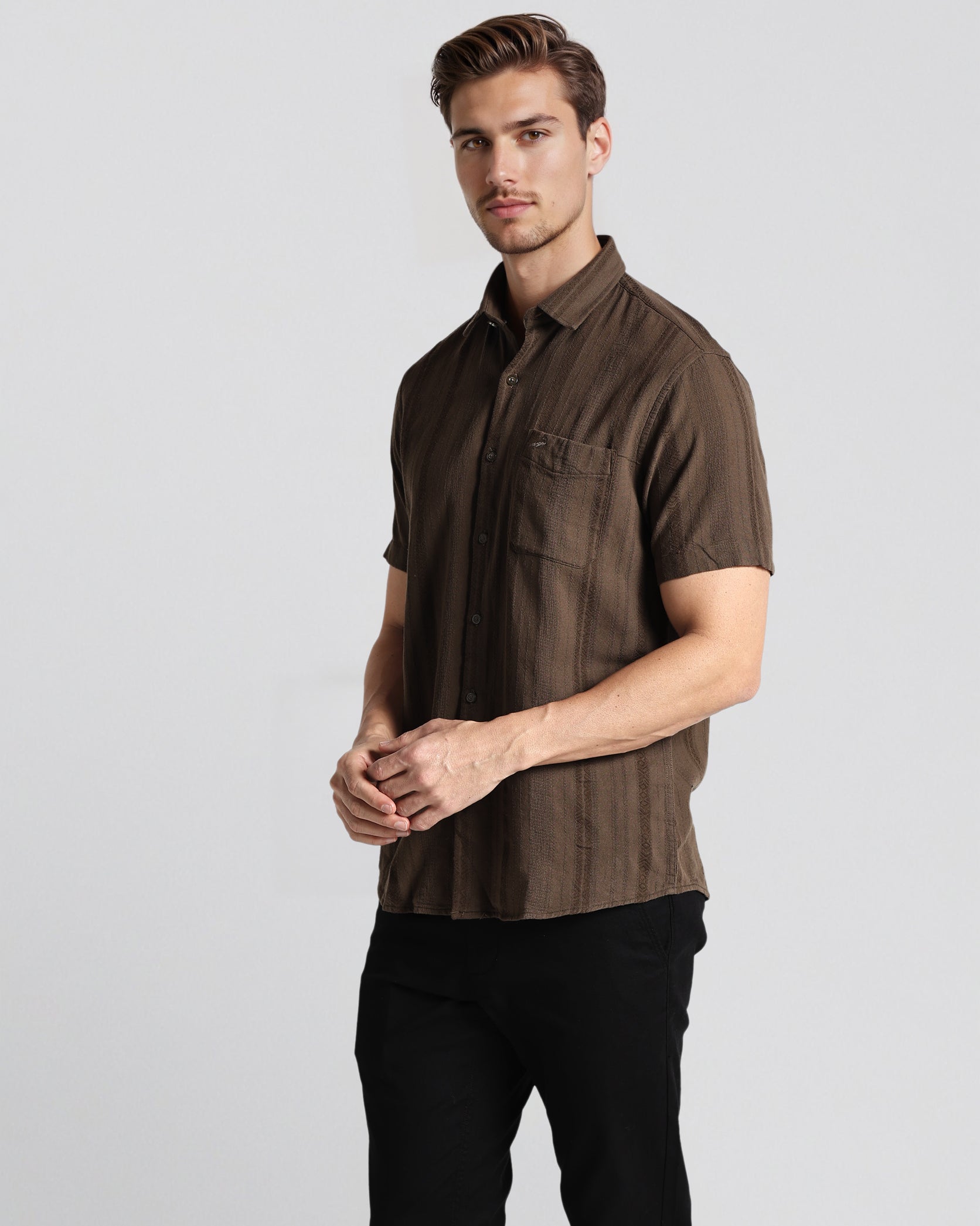 Man wearing a brown short-sleeve shirt on a light gray background