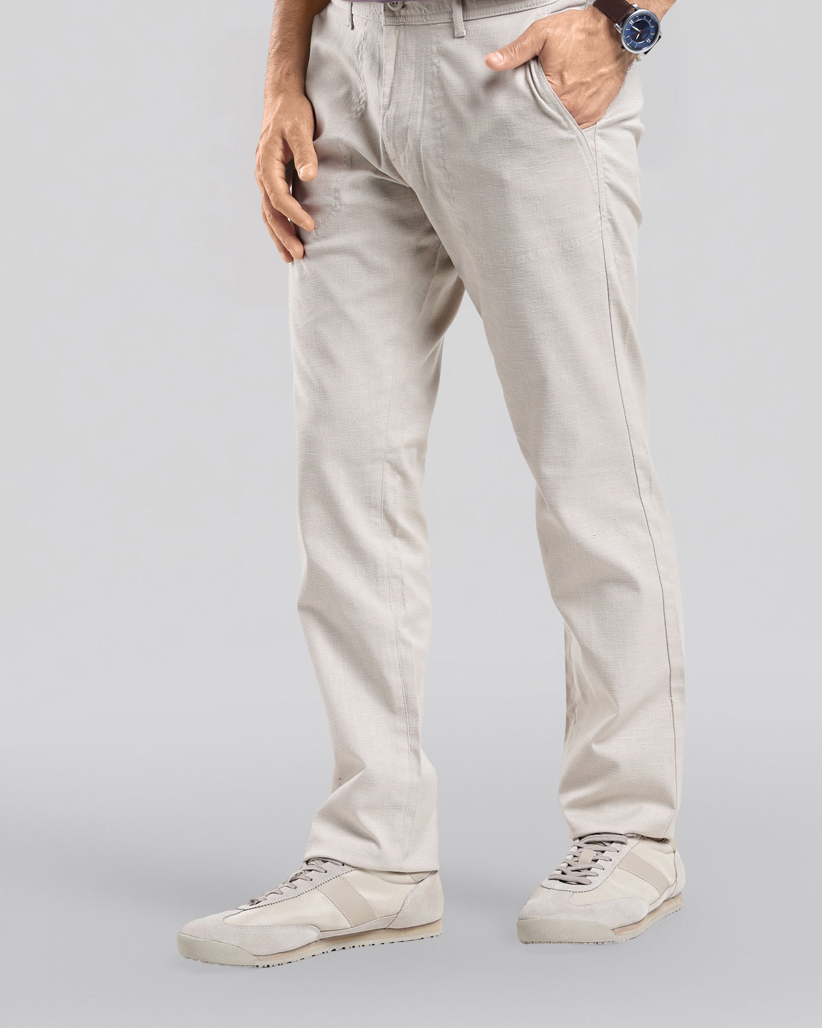 Person wearing light-colored pants and a striped shirt on a plain background