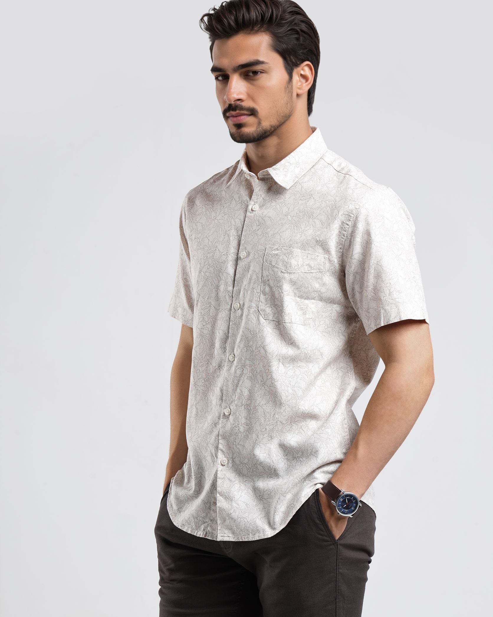 Man wearing a white short-sleeve shirt and dark pants on a light gray background