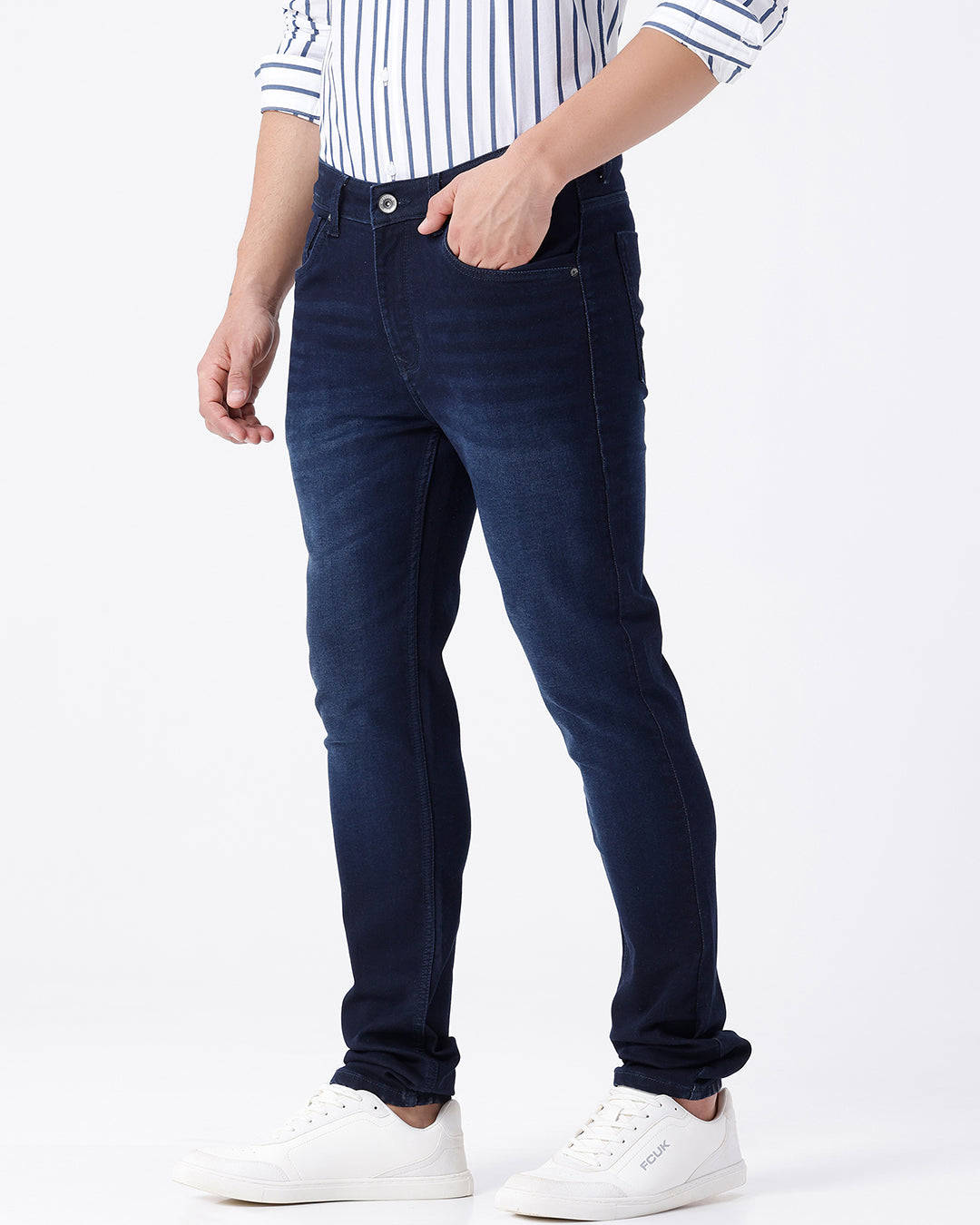 Man wearing a blue dark blue knit slim fit jeans with casual styling on a gray background