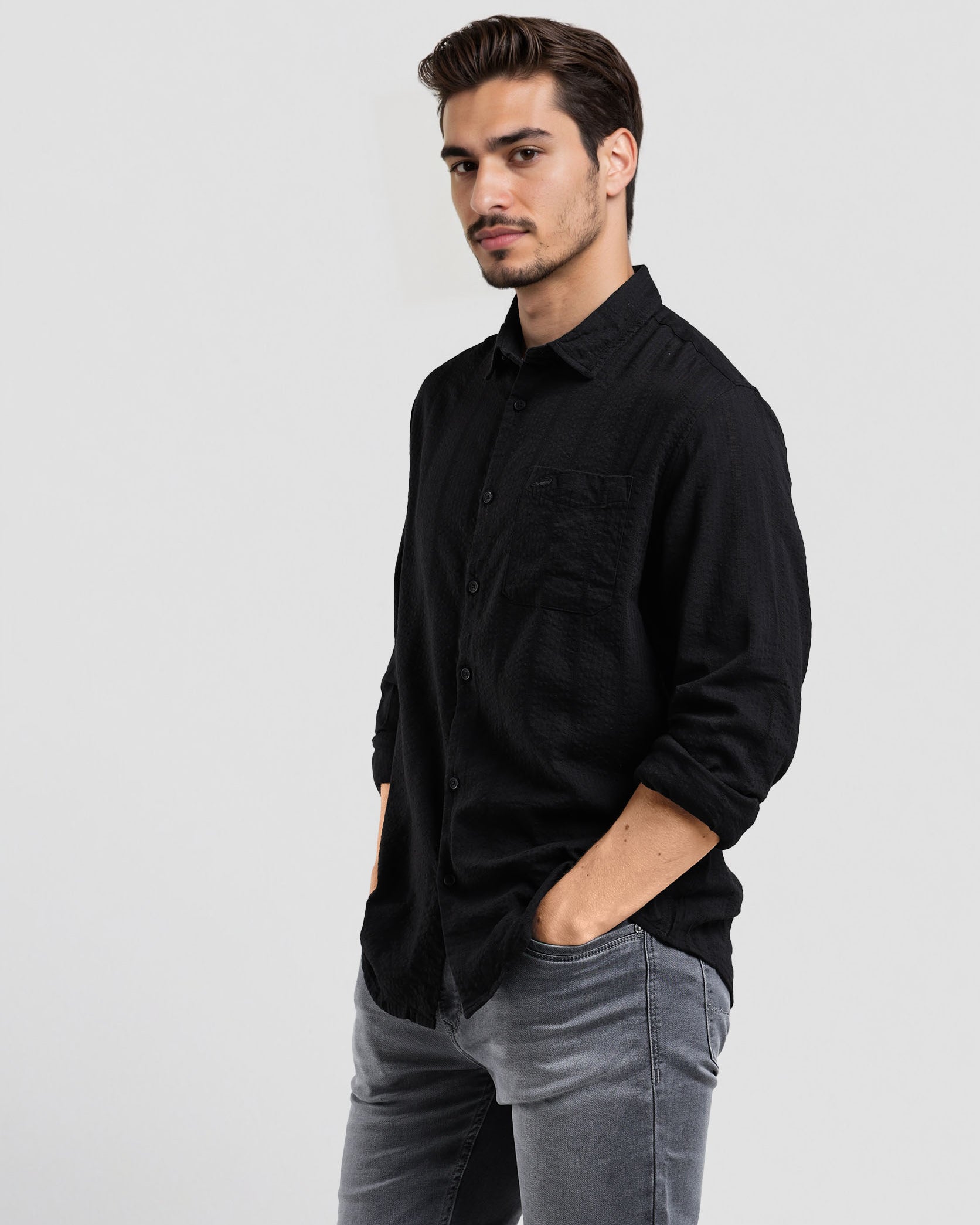 Man wearing a black shirt and gray pants on a white background