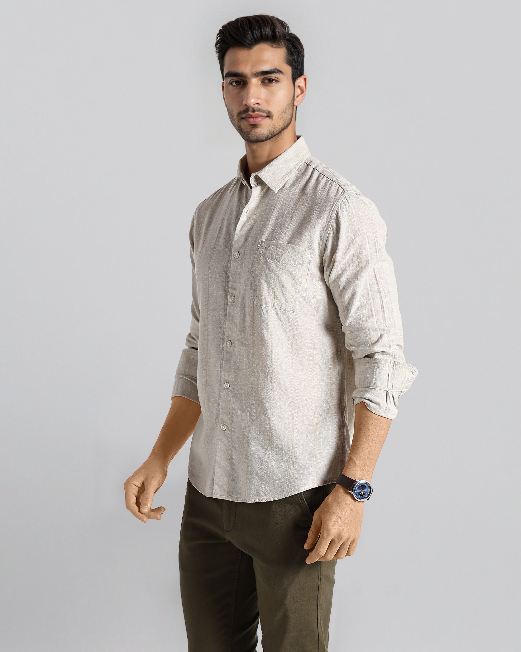 Man wearing a light-colored shirt and dark pants on a gray background