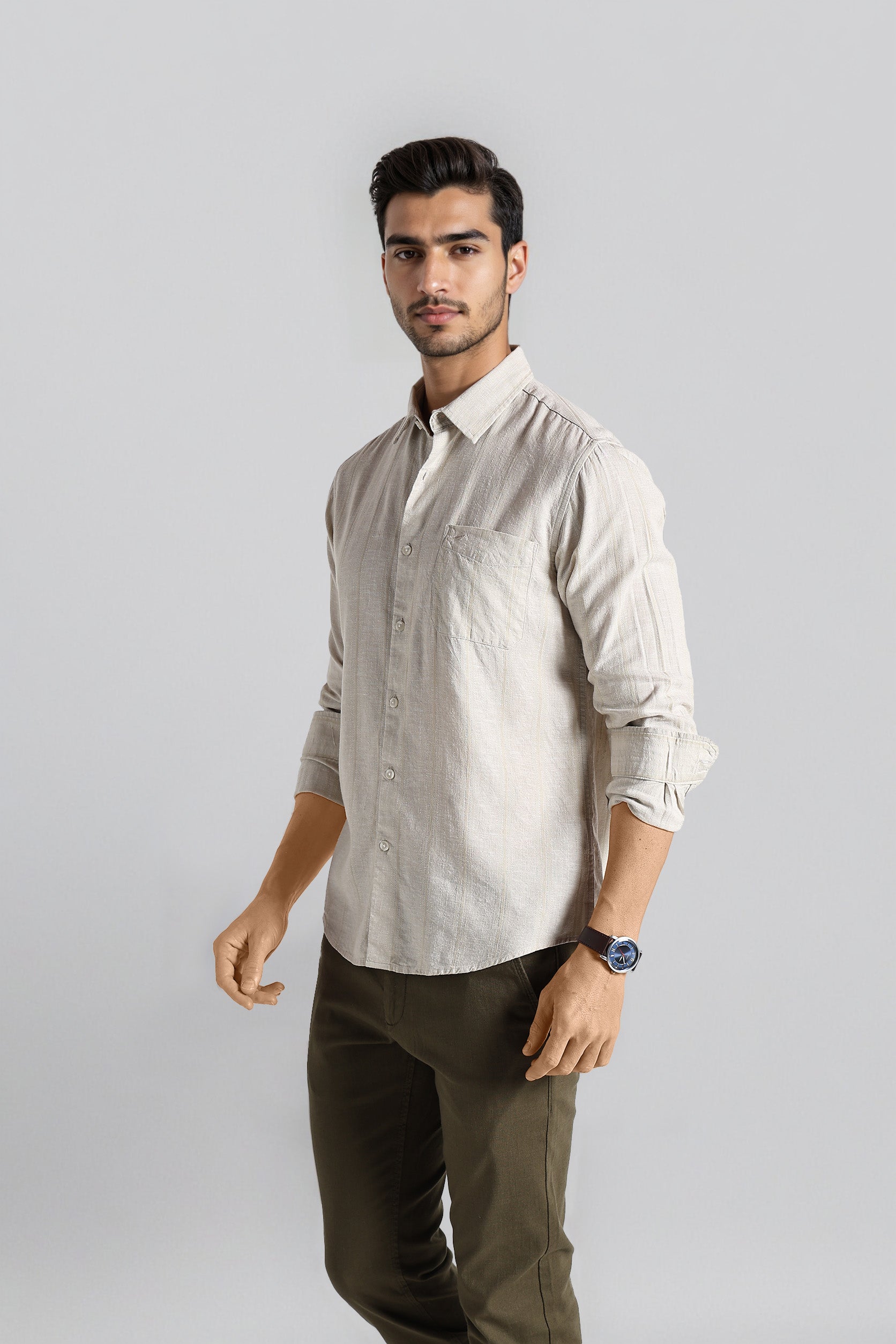 Man wearing a light-colored shirt and dark pants on a gray background