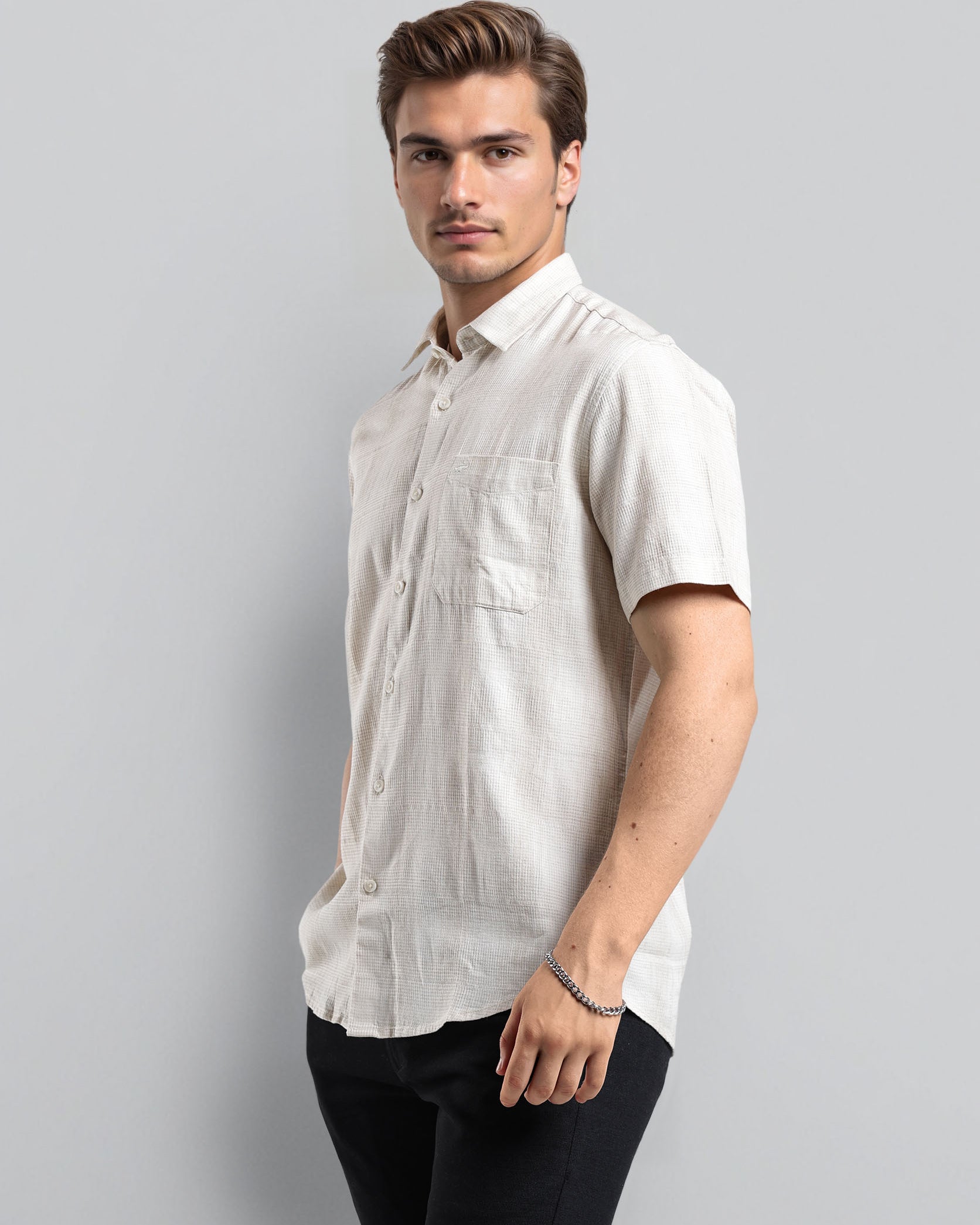 Man wearing a white short-sleeve shirt against a gray background