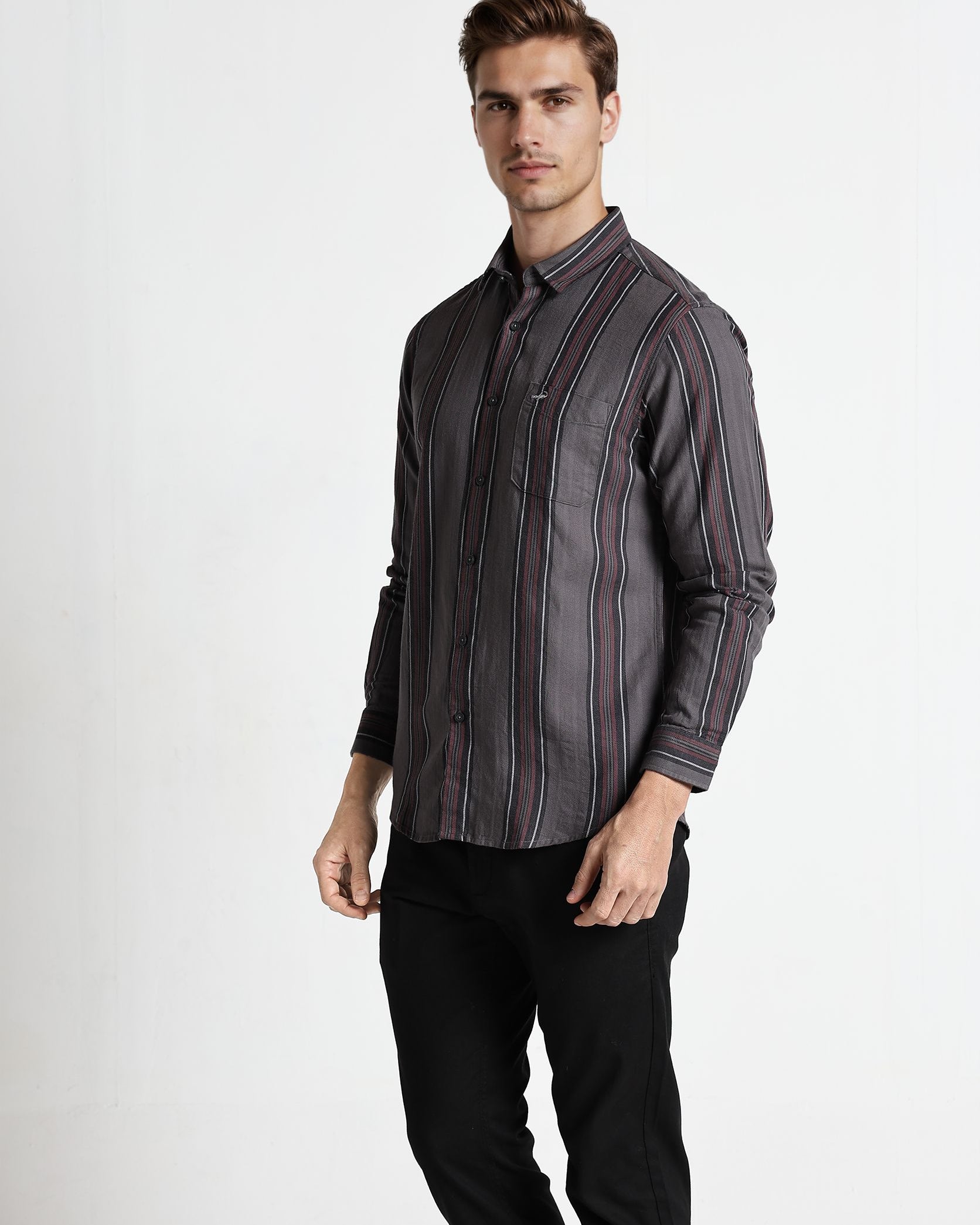 Man wearing a striped shirt and black pants on a white background