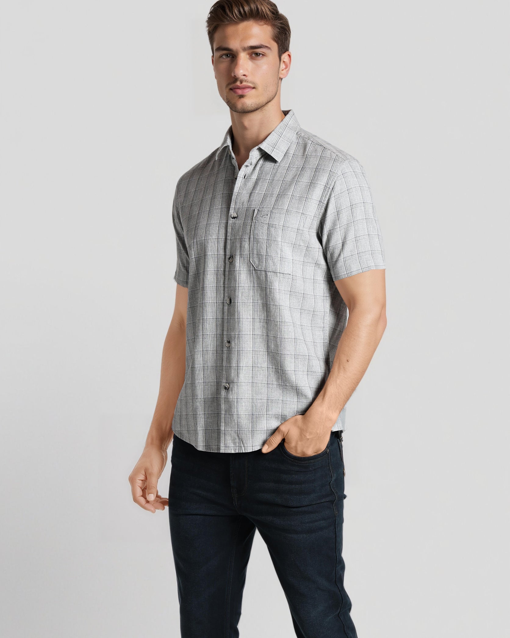 Man wearing a checkered shirt and dark pants on a light gray background