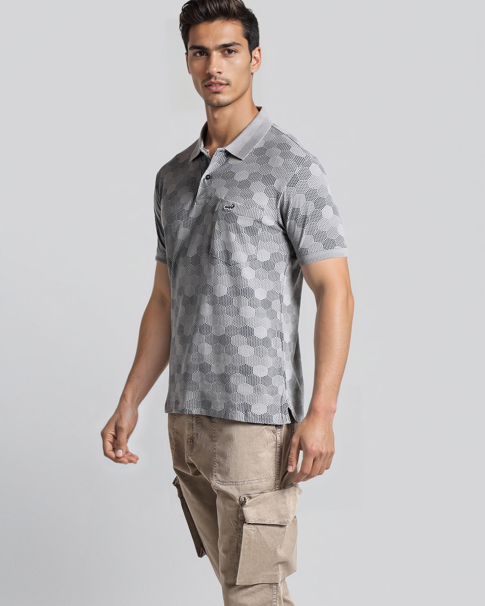 Man wearing a gray patterned polo shirt and beige cargo pants on a light gray background