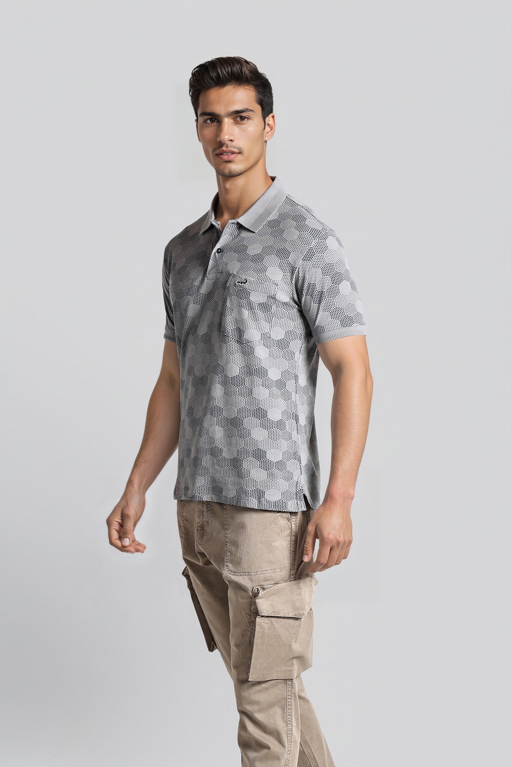 Man wearing a gray patterned polo shirt and beige cargo pants on a light gray background