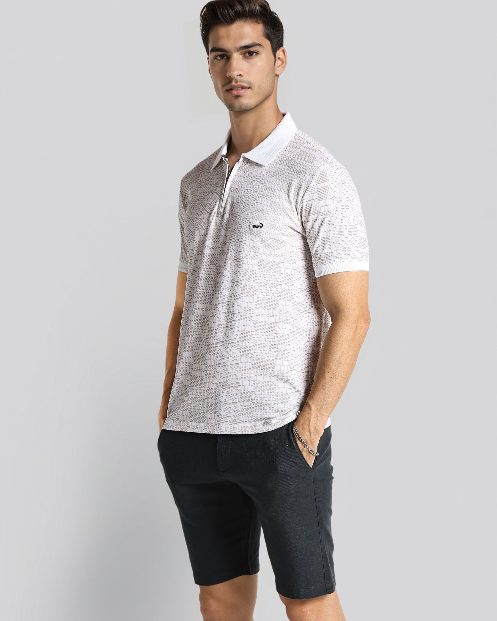 Man wearing a light gray polo shirt and black shorts on a white background