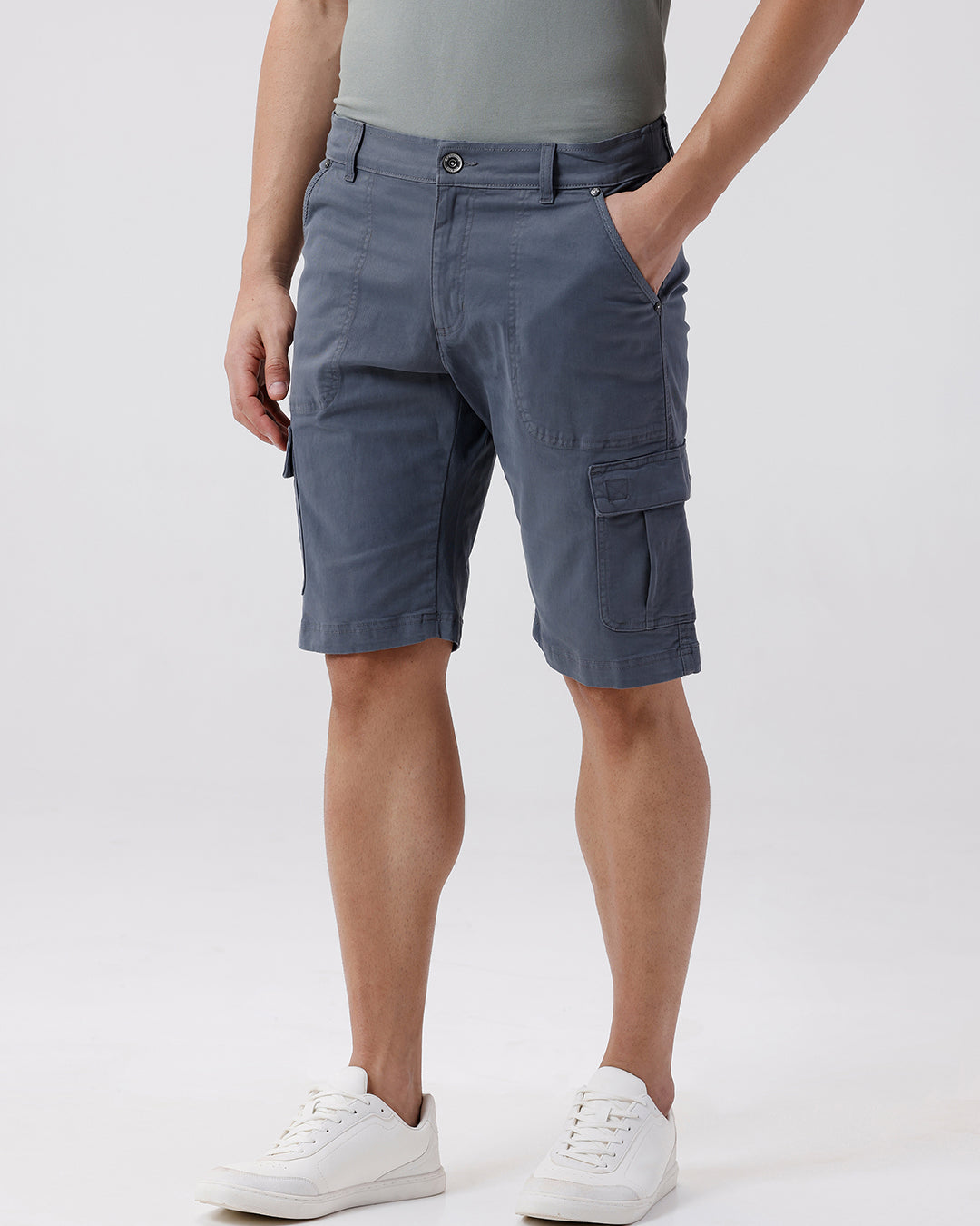 Man wearing a grey garment dyed cargo shorts in dark grey with casual styling on a gray background