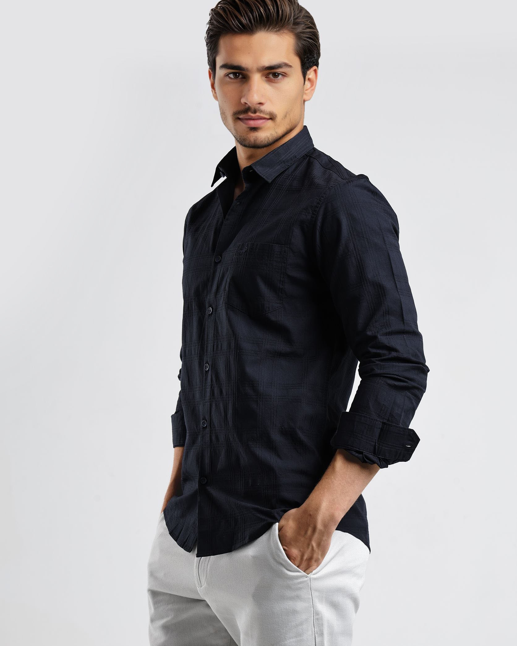 Man wearing a black shirt and white pants on a light gray background