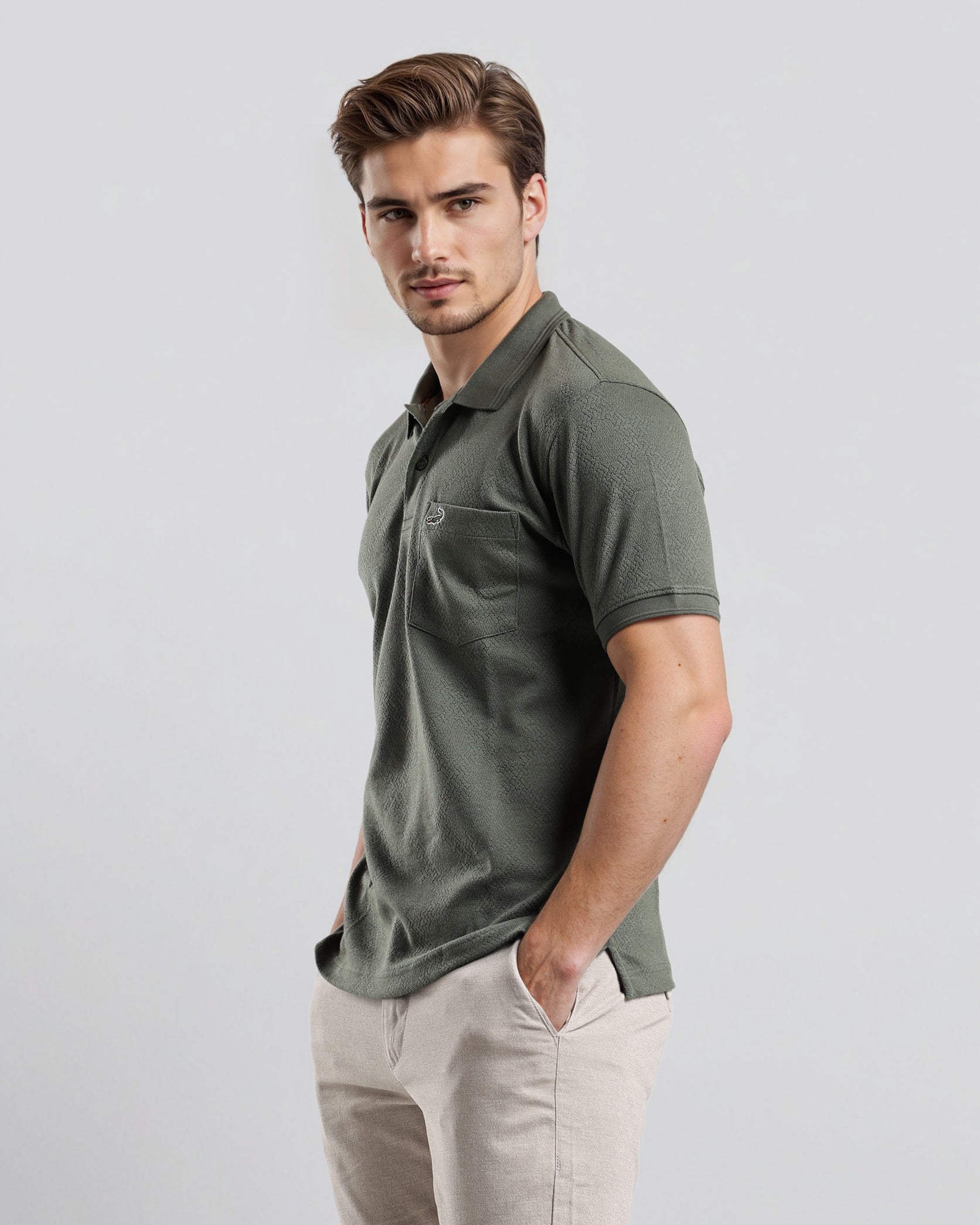 Man wearing a green polo shirt and beige pants on a light gray background