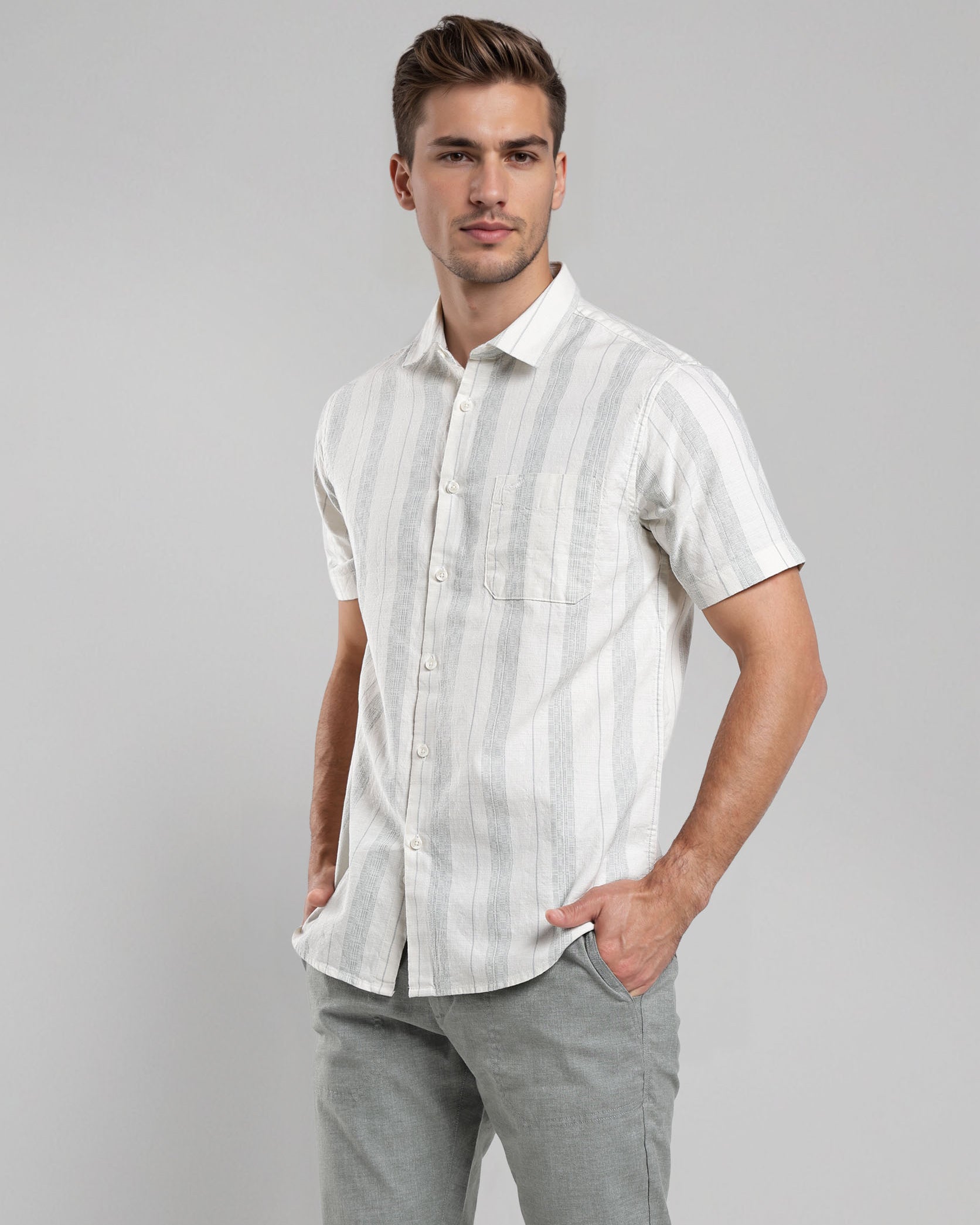 Man wearing a white striped shirt and gray pants on a gray background