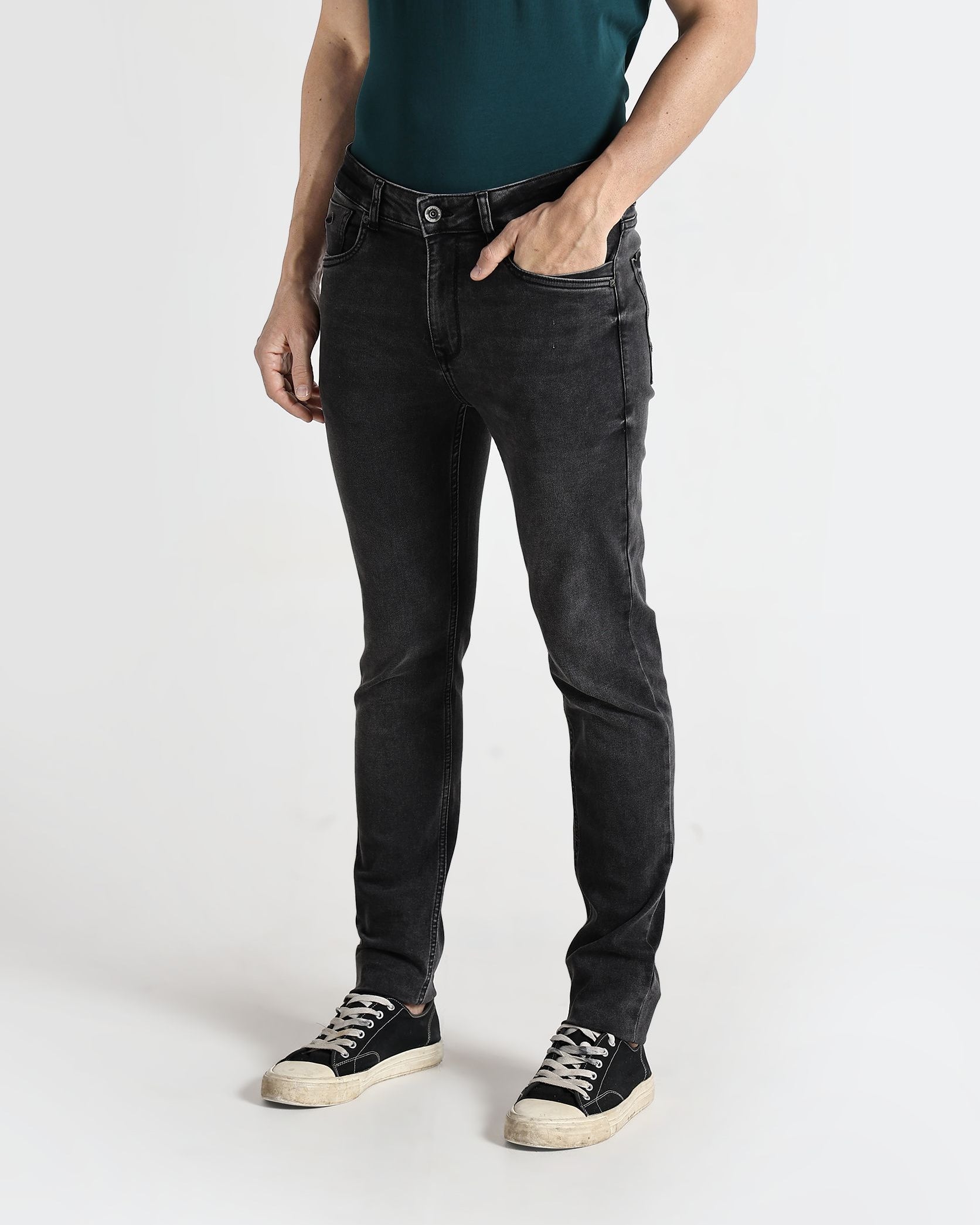 Person wearing black jeans and a green shirt on a white background