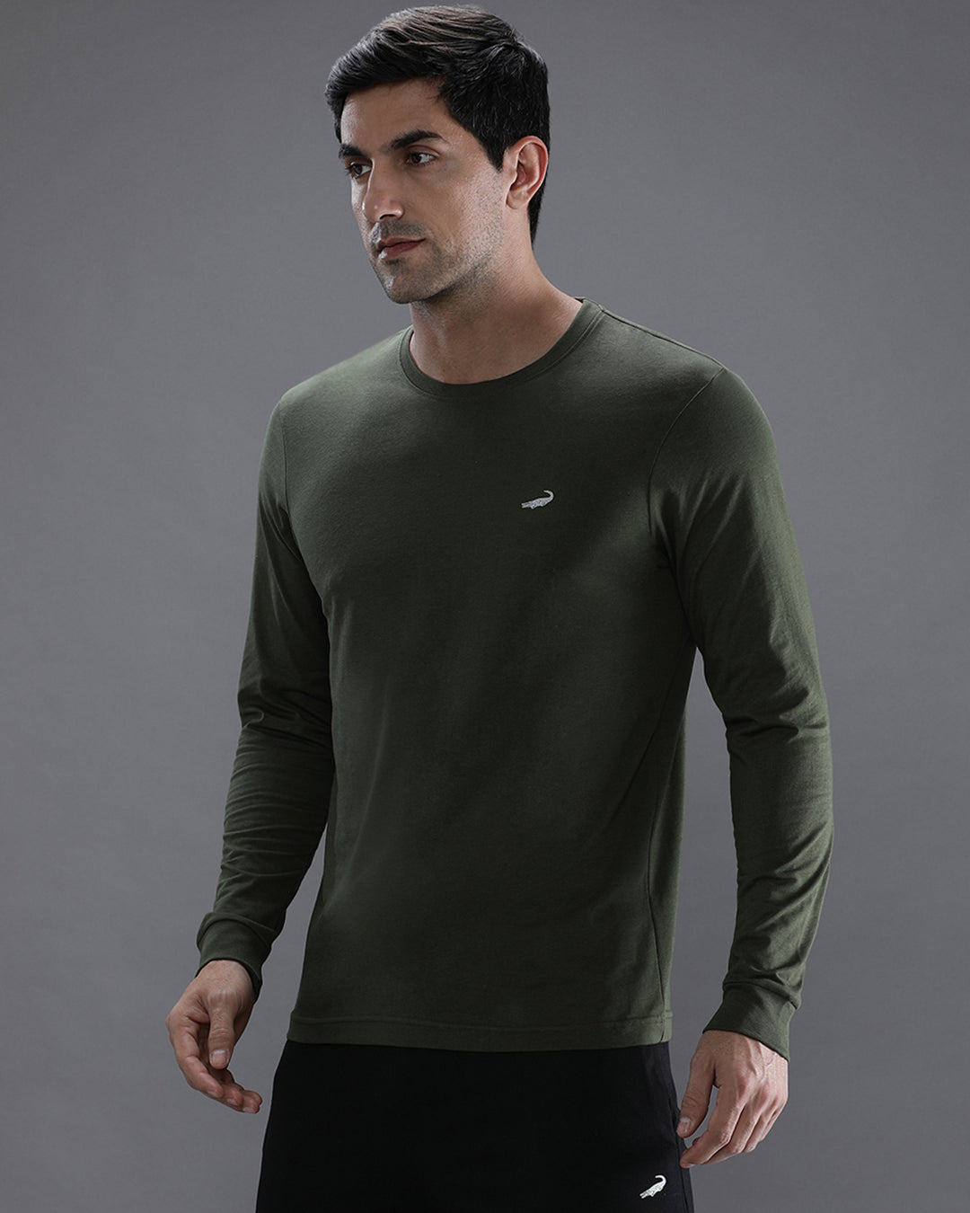 Man wearing a green solid green sport fit t shirt with casual styling on a gray background