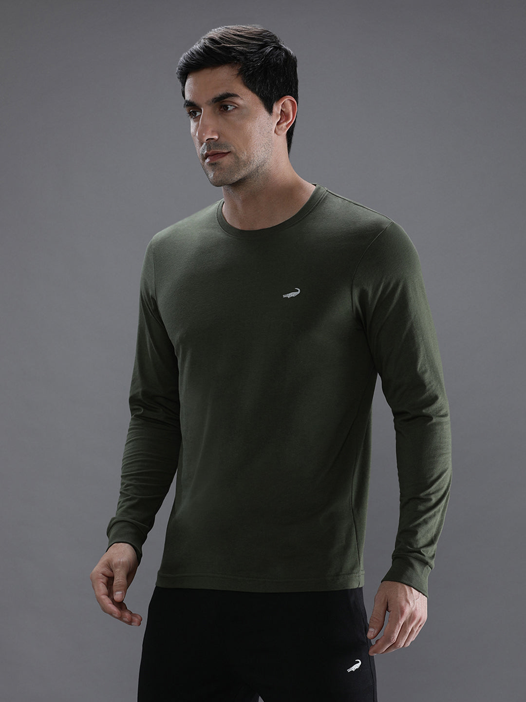 Man wearing a green solid green sport fit t shirt with casual styling on a gray background