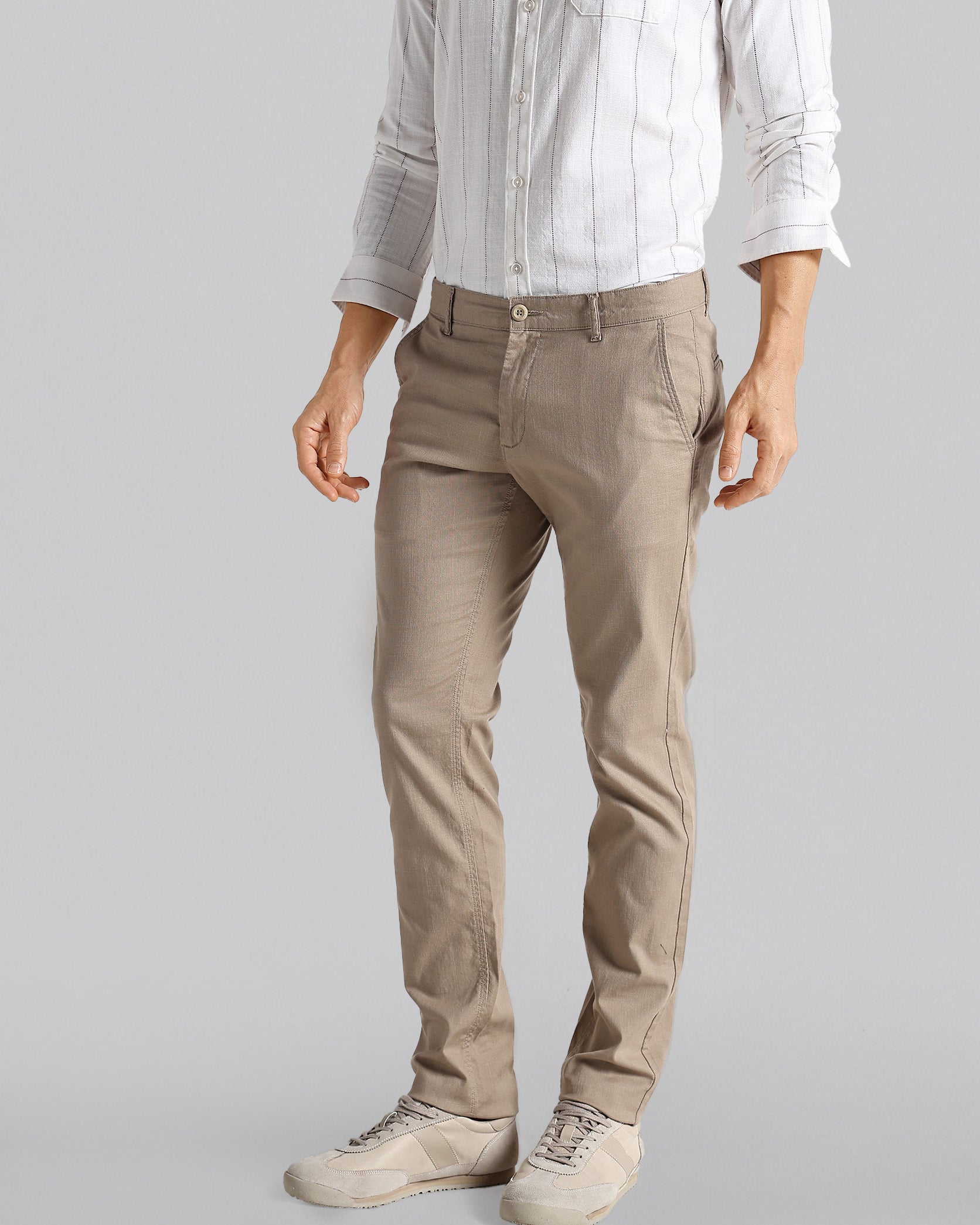 Person wearing beige pants and a light shirt on a gray background