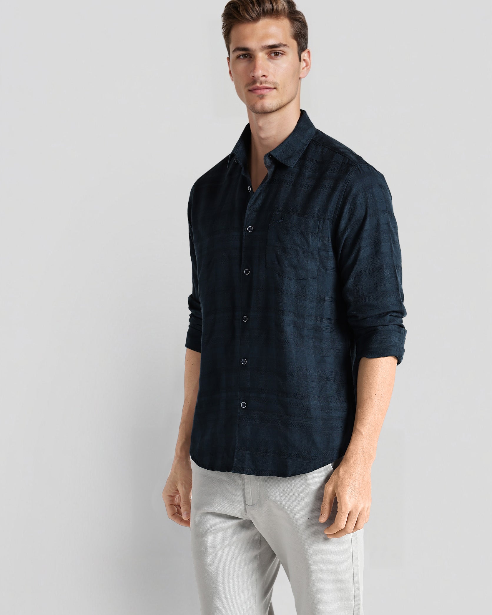 Man wearing a dark blue shirt and light gray pants on a white background