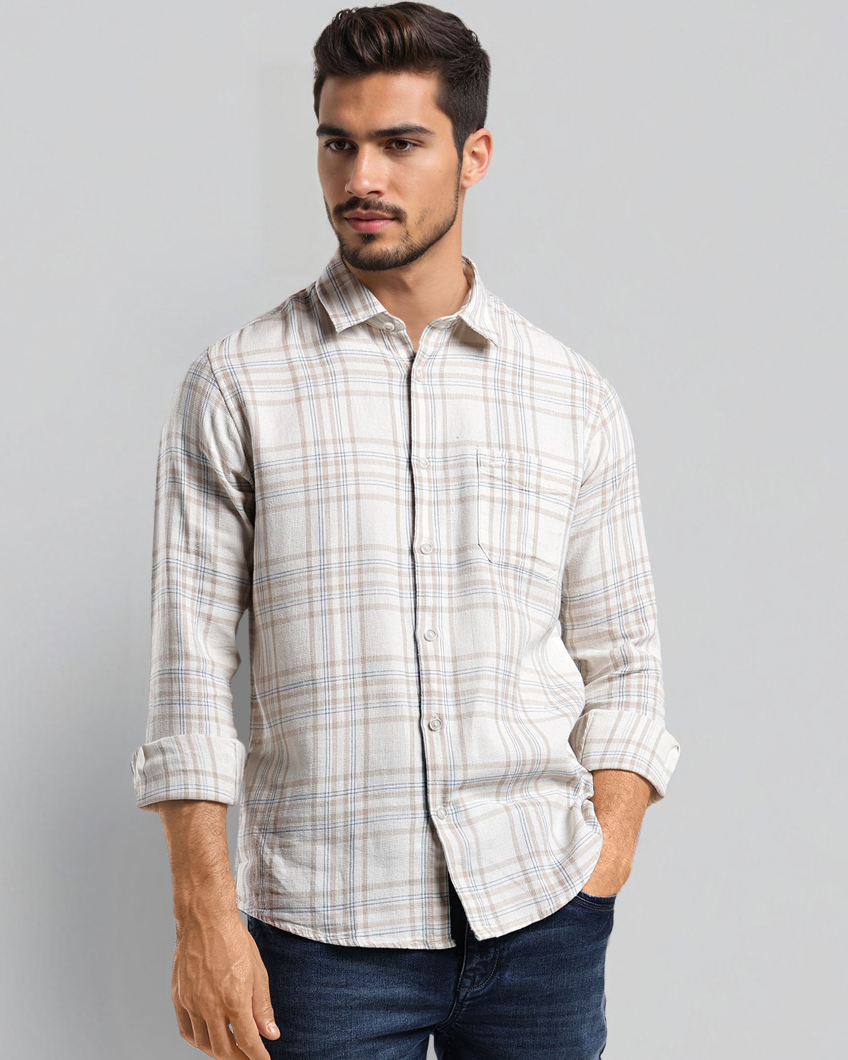 Man wearing a checkered shirt and jeans on a gray background